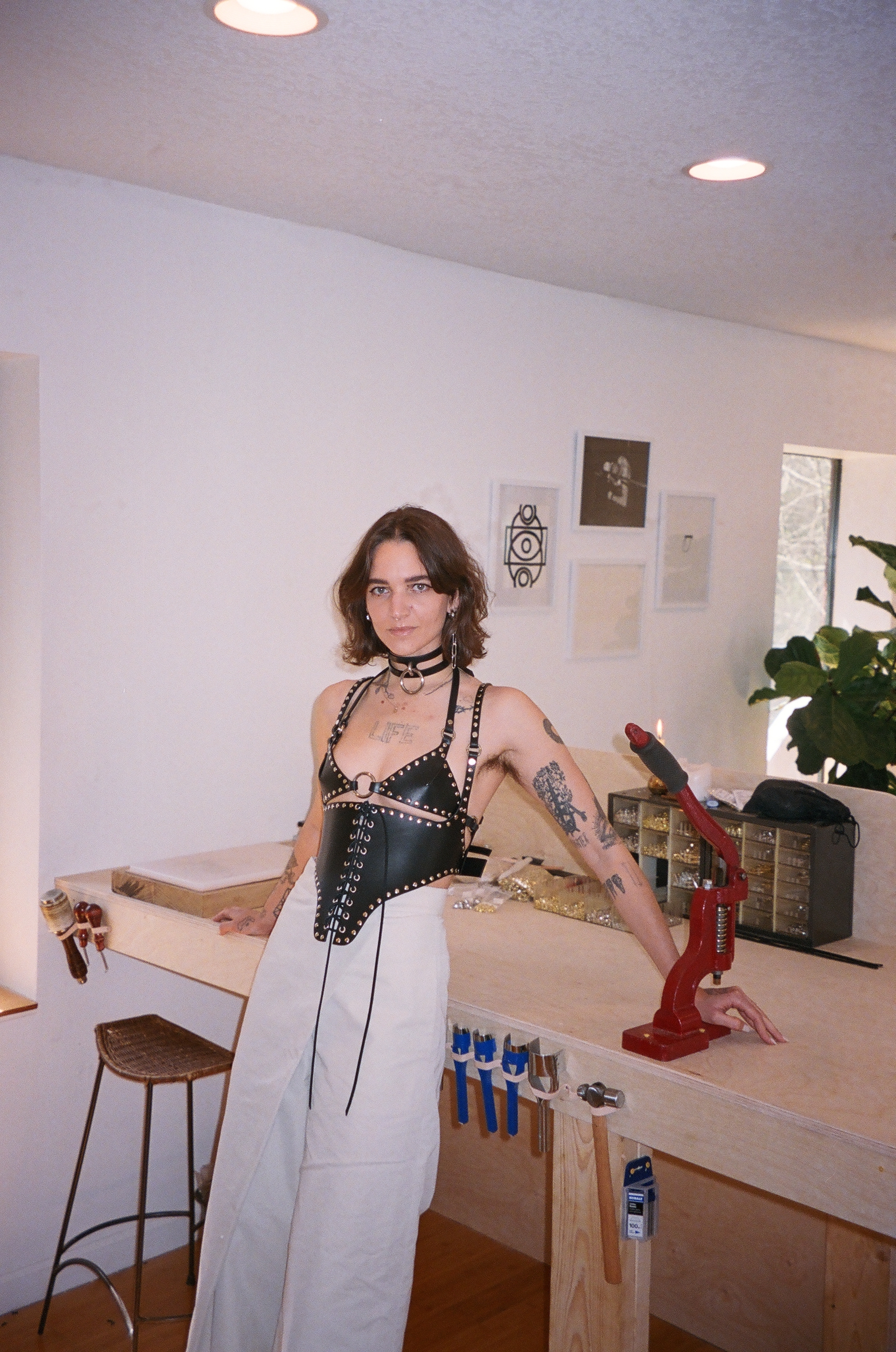 hunter savoy in a leather harness leaning against her work table