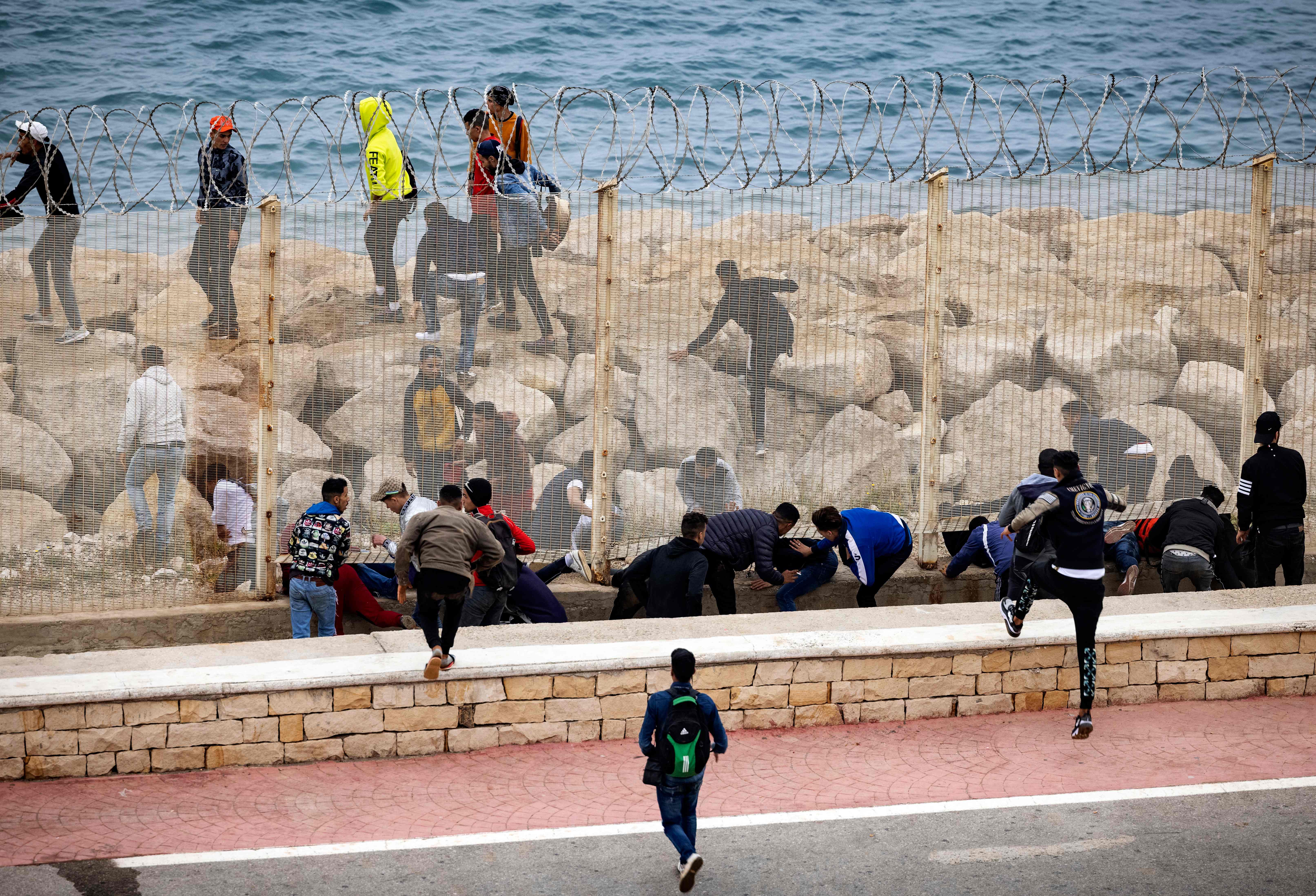 People slip through a border fence on Tuesday. Photo: FADEL SENNA/AFP via Getty Images
