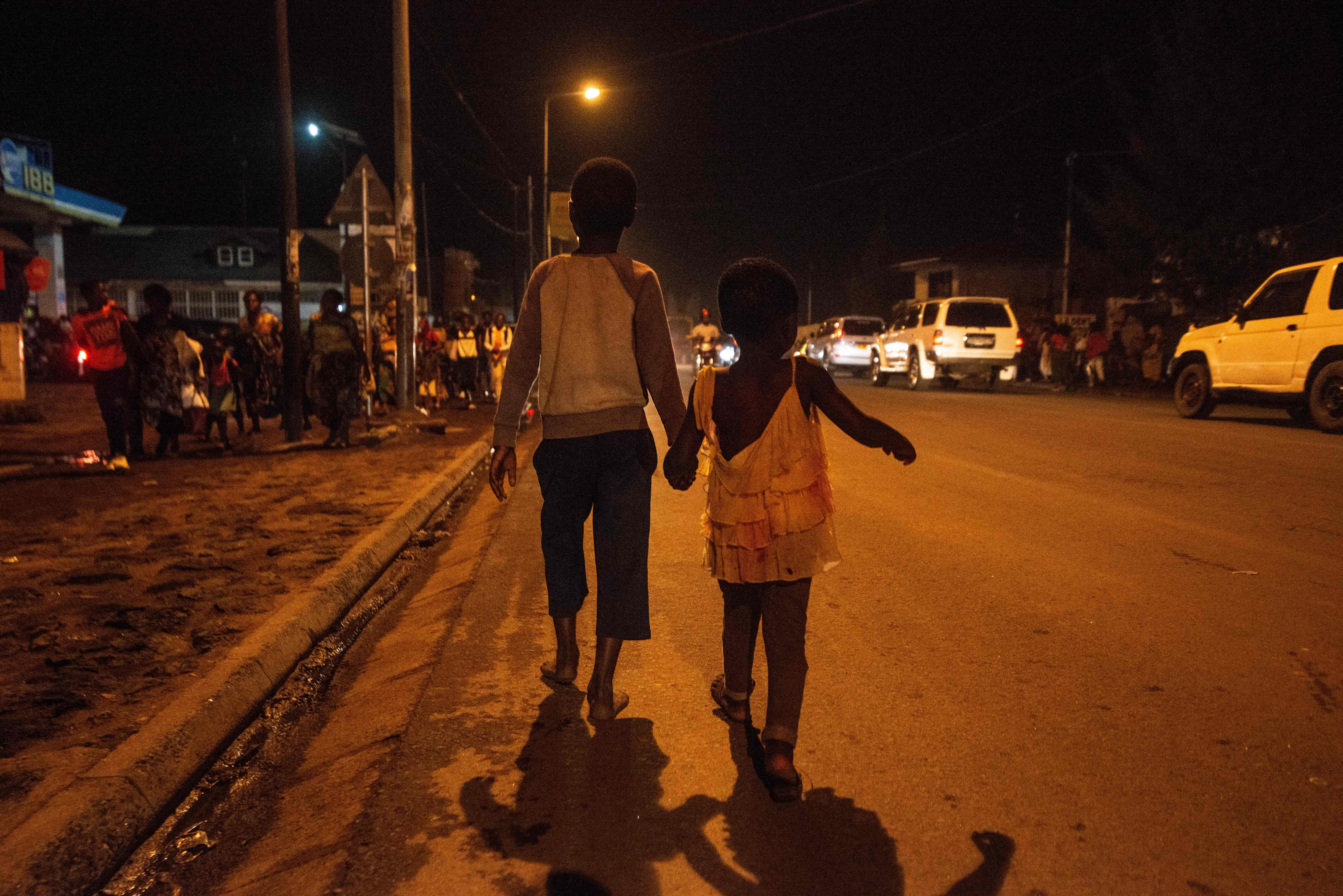 Dua anak berjalan sambil bergandengan tangan.