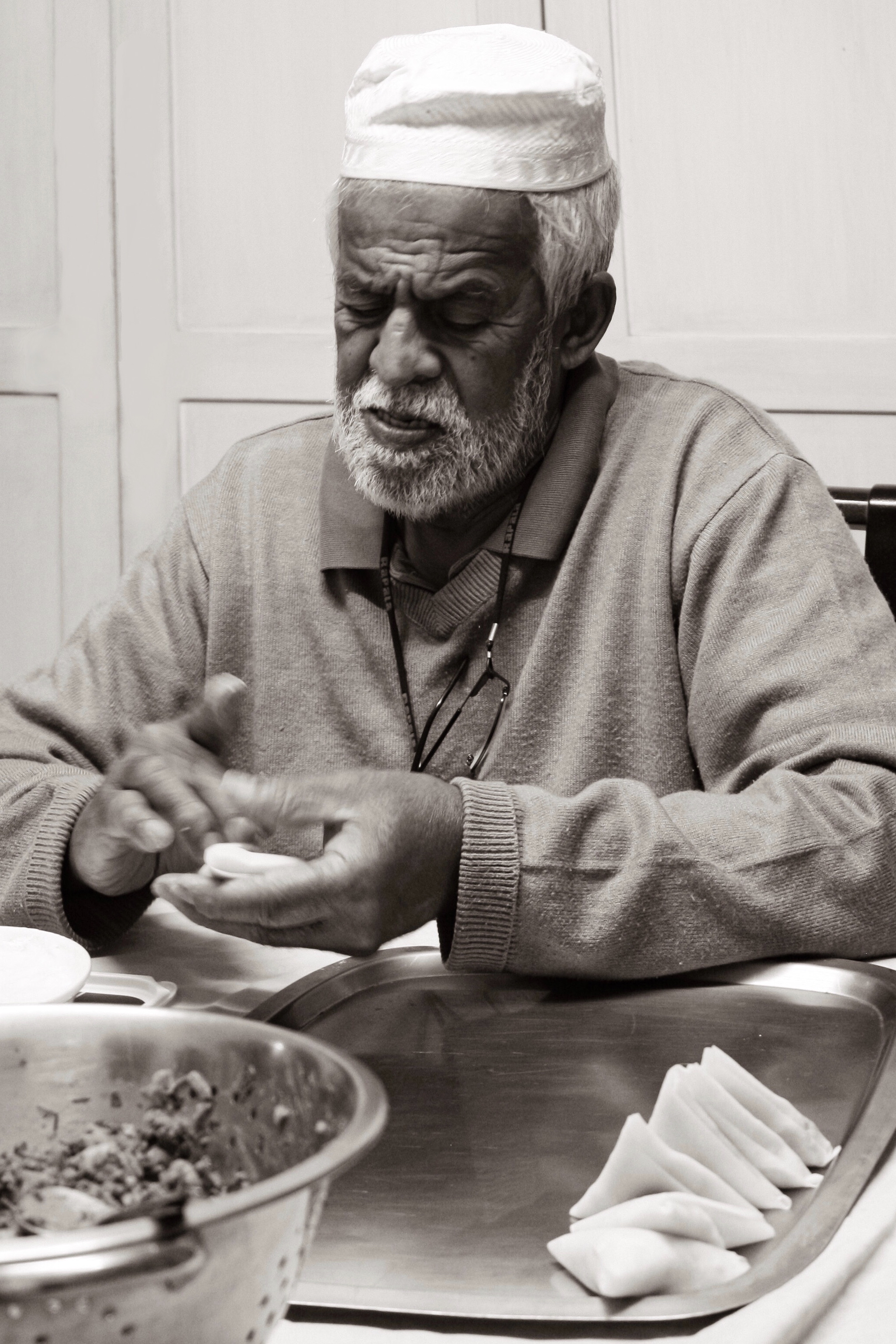 An old man folding samoosas.