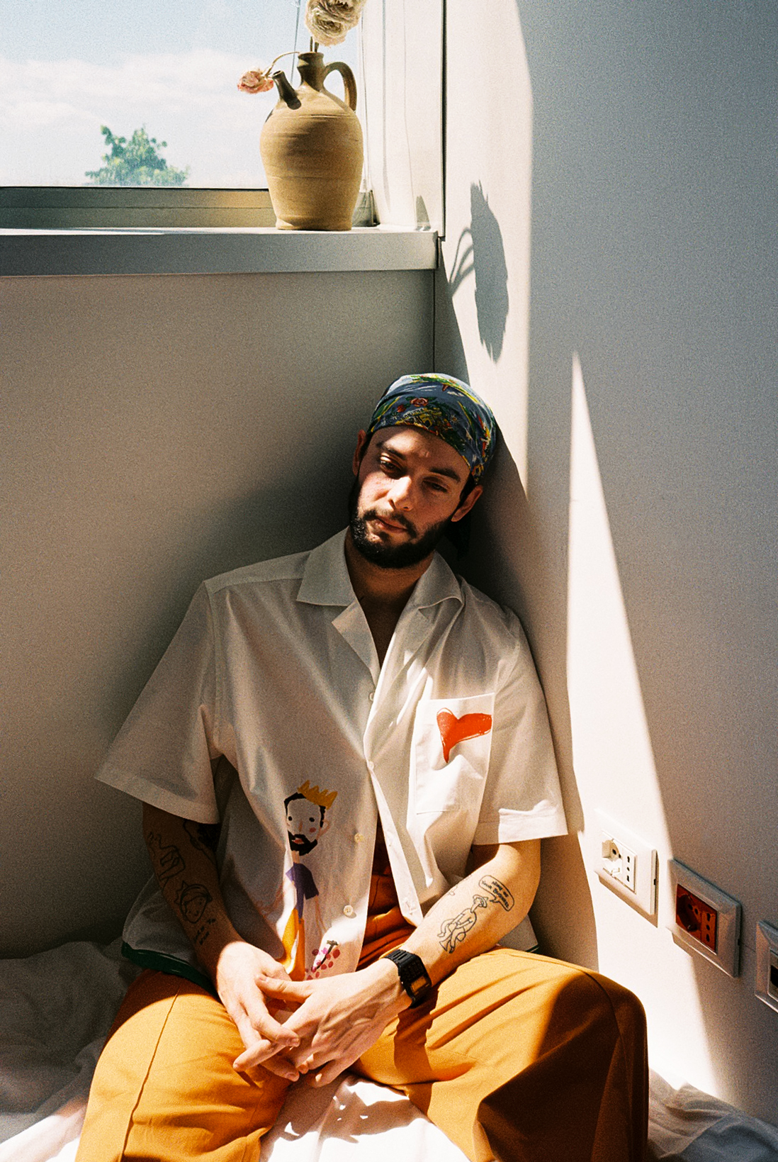 foto di francesco cicconetti mehths seduto su un letto sotto una finestra con indosso a-o bowling shirt di Federico Cina, foto Sara lorusso