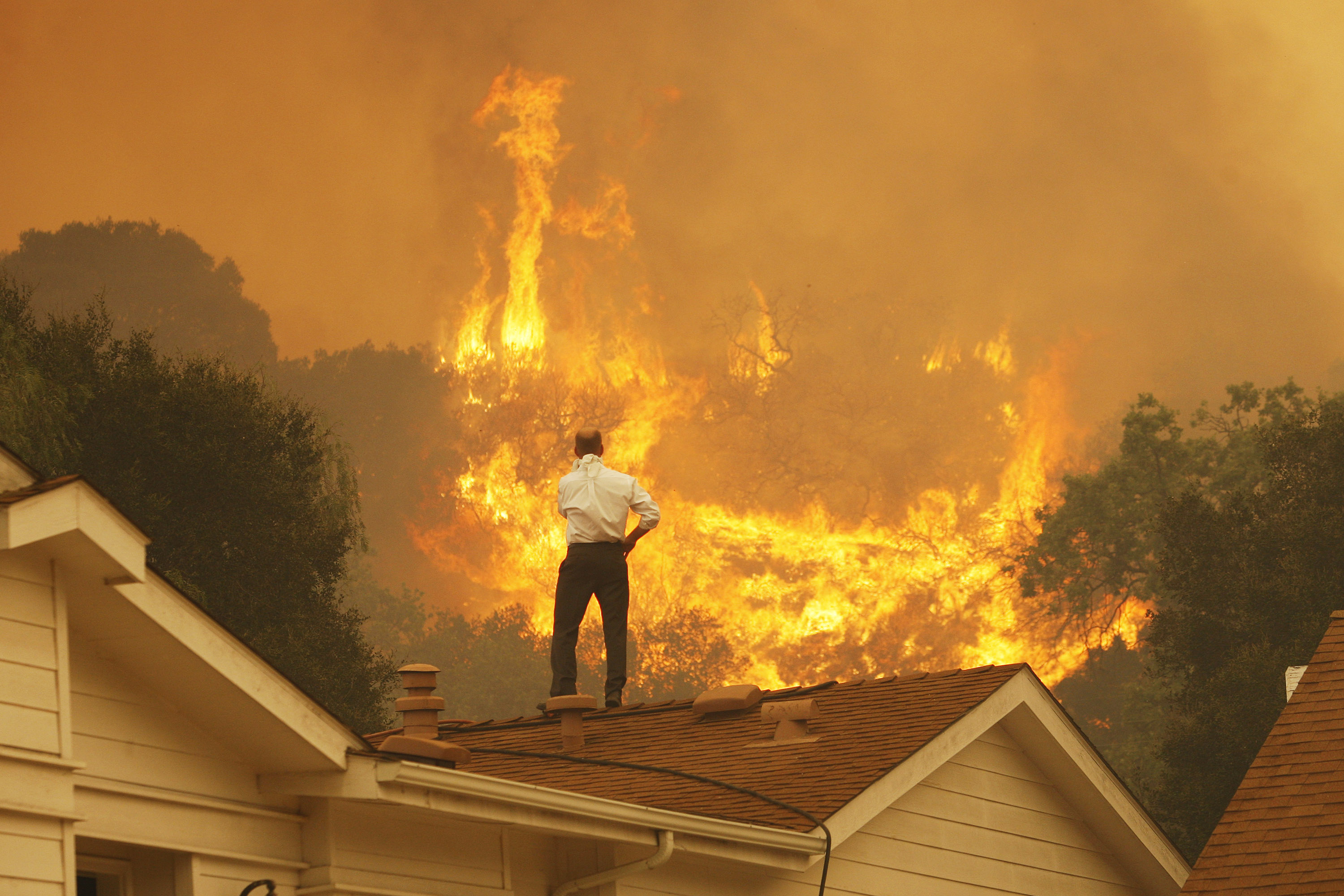 A man on a rooftop looks at approaching flames as wildfires grow near Camarillo, California, in May 2013. Photo: David McNew/Getty Images