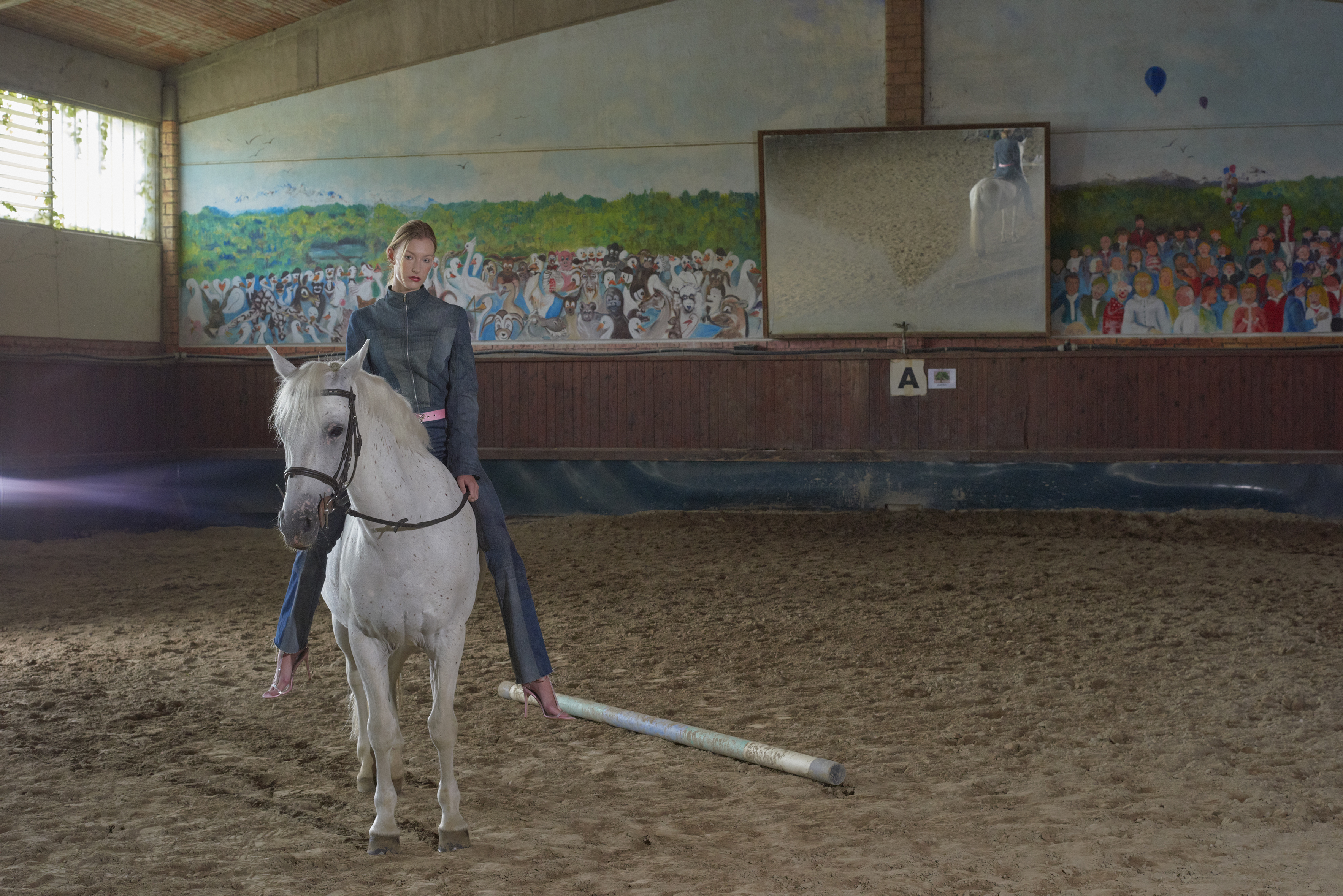 modella a cavallo in mezzo a una pista di sabbia da equitazione