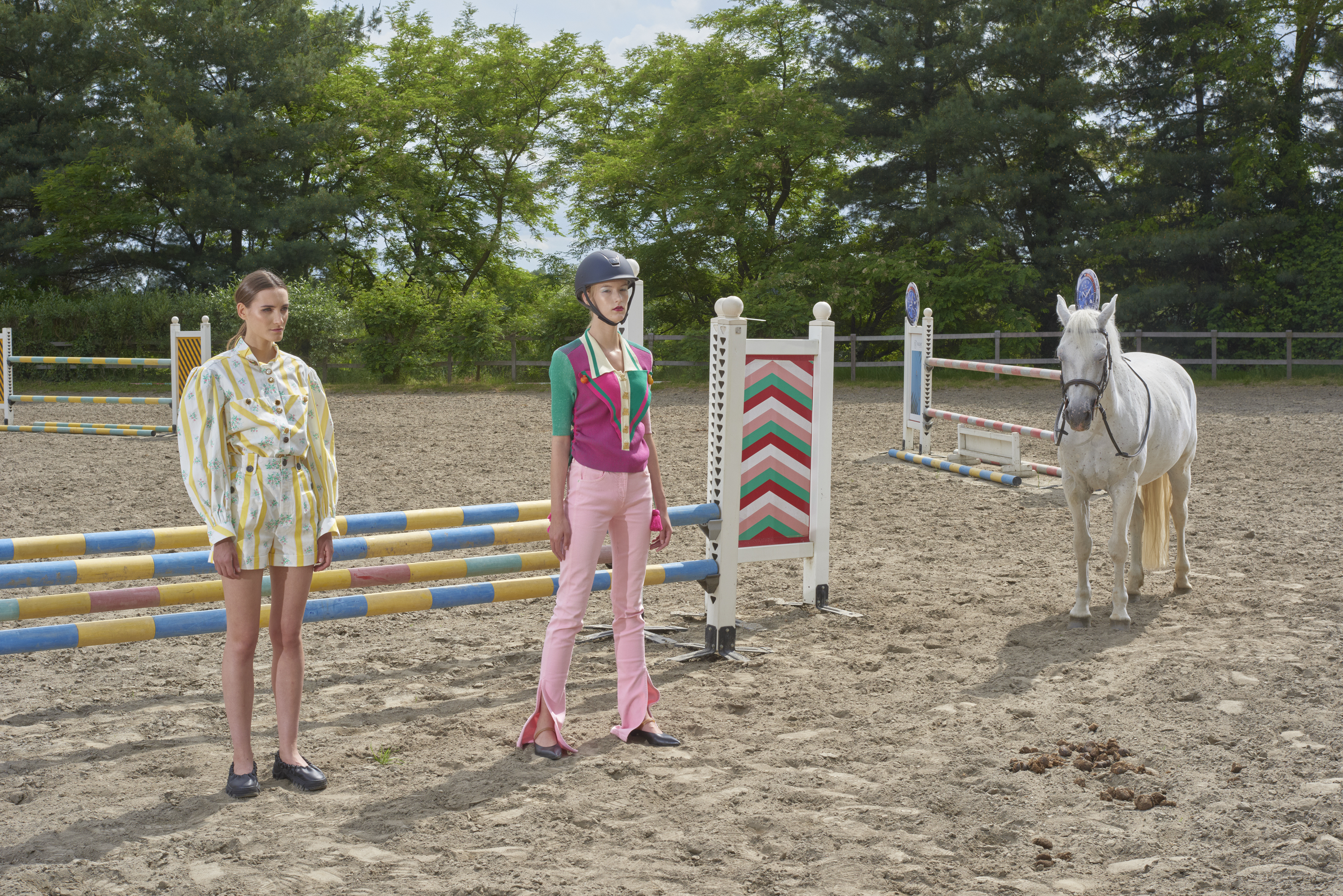 modelle davanti a ostacoli da equitazione in una pista di sabbia con un cavallo bianco