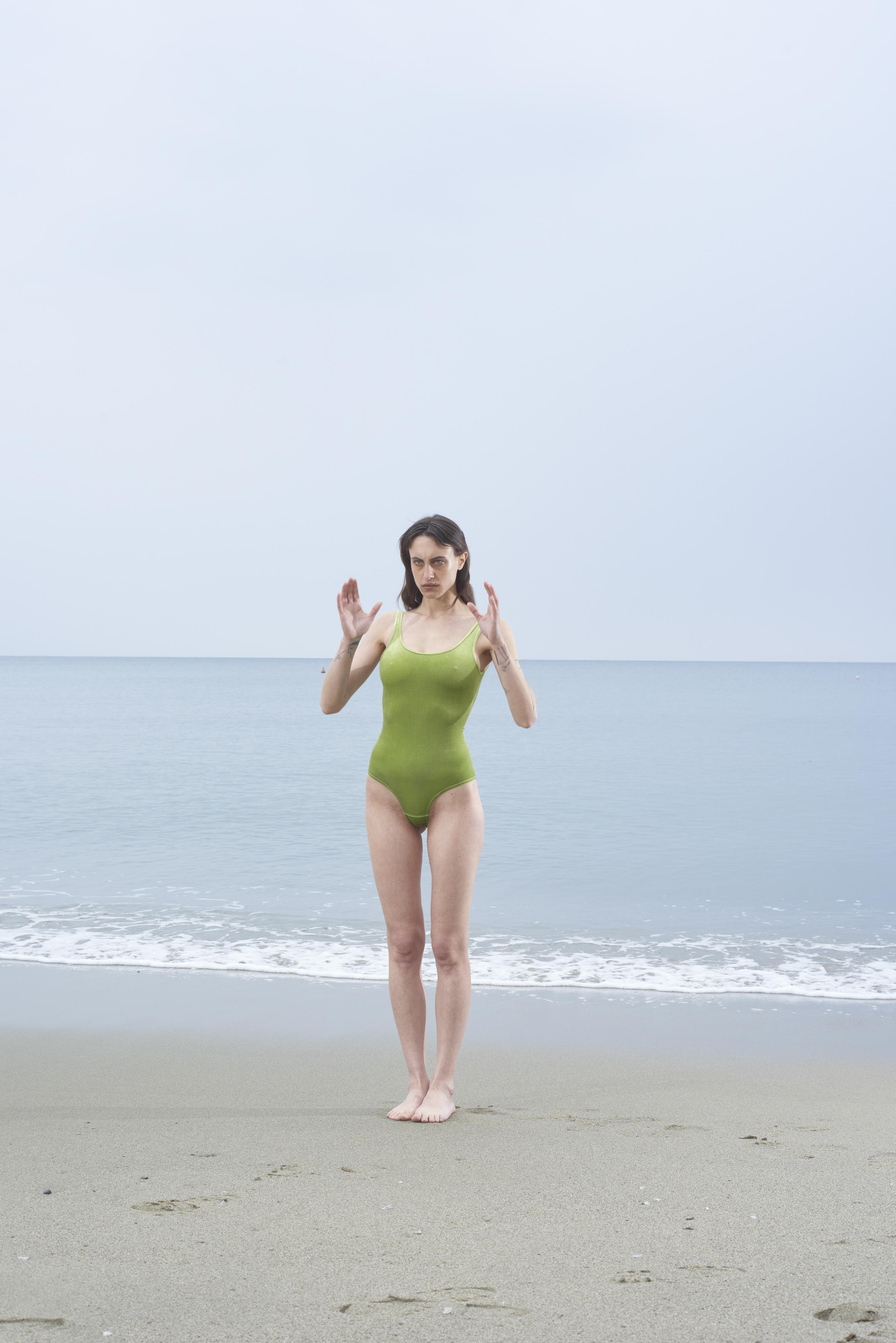 modella con costume verde davanti al mare in spiaggia post-sovietica