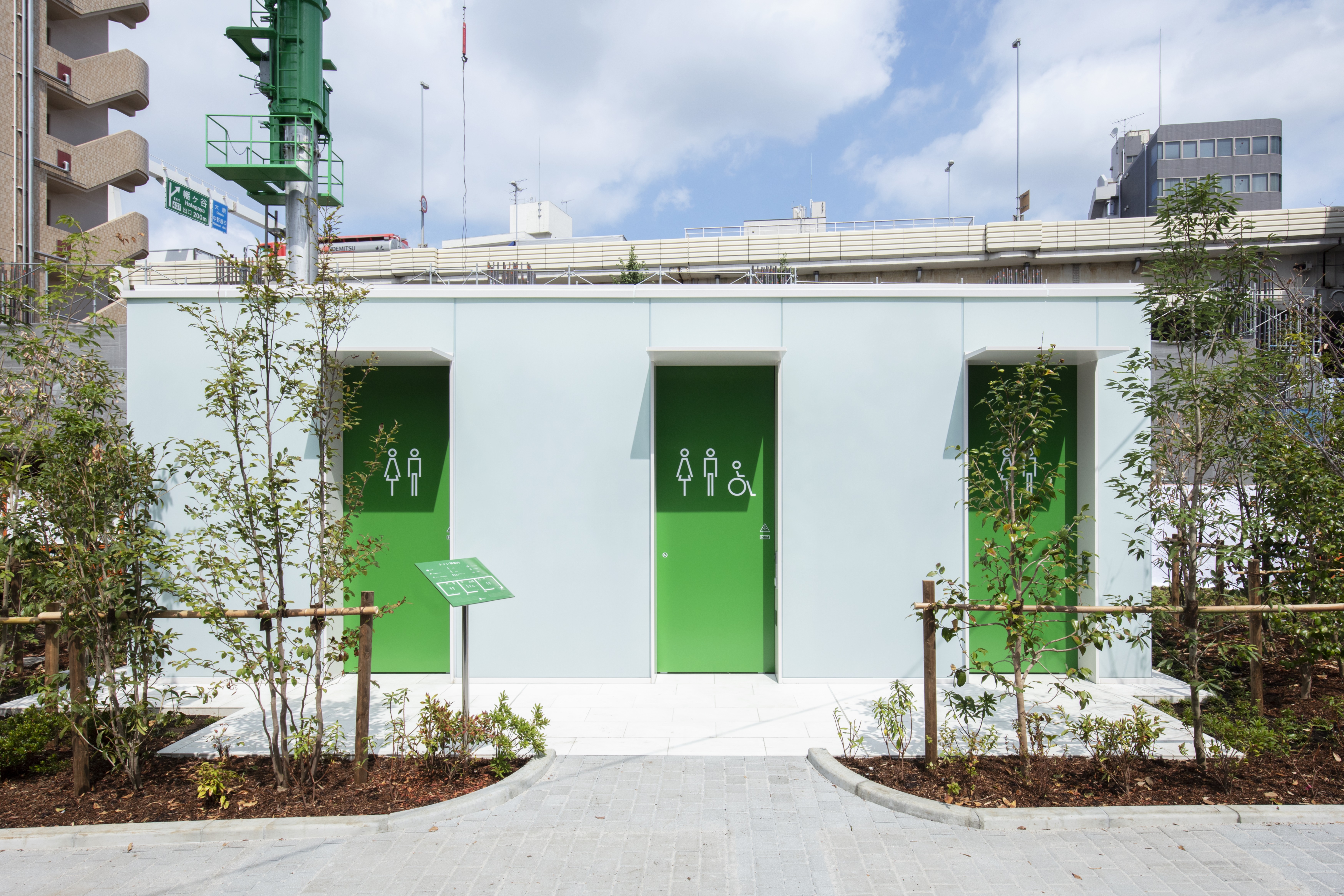 Toilet umum berwarna putih dengan pintu hijau terang.