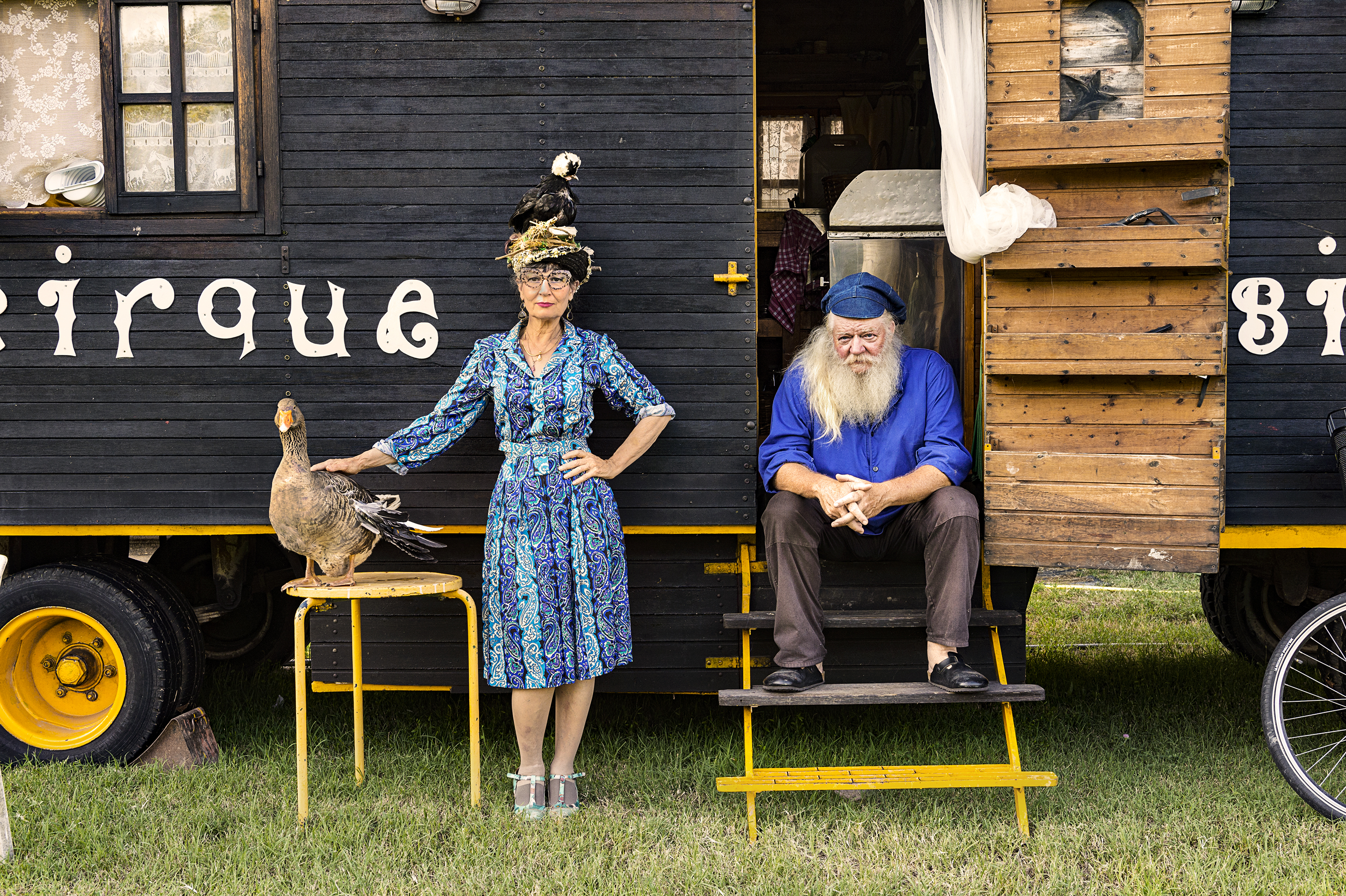 una donna con un'oca e un uomo seduto sulle scale davanti a una roulotte da circo foto di Stephanie Gengotti