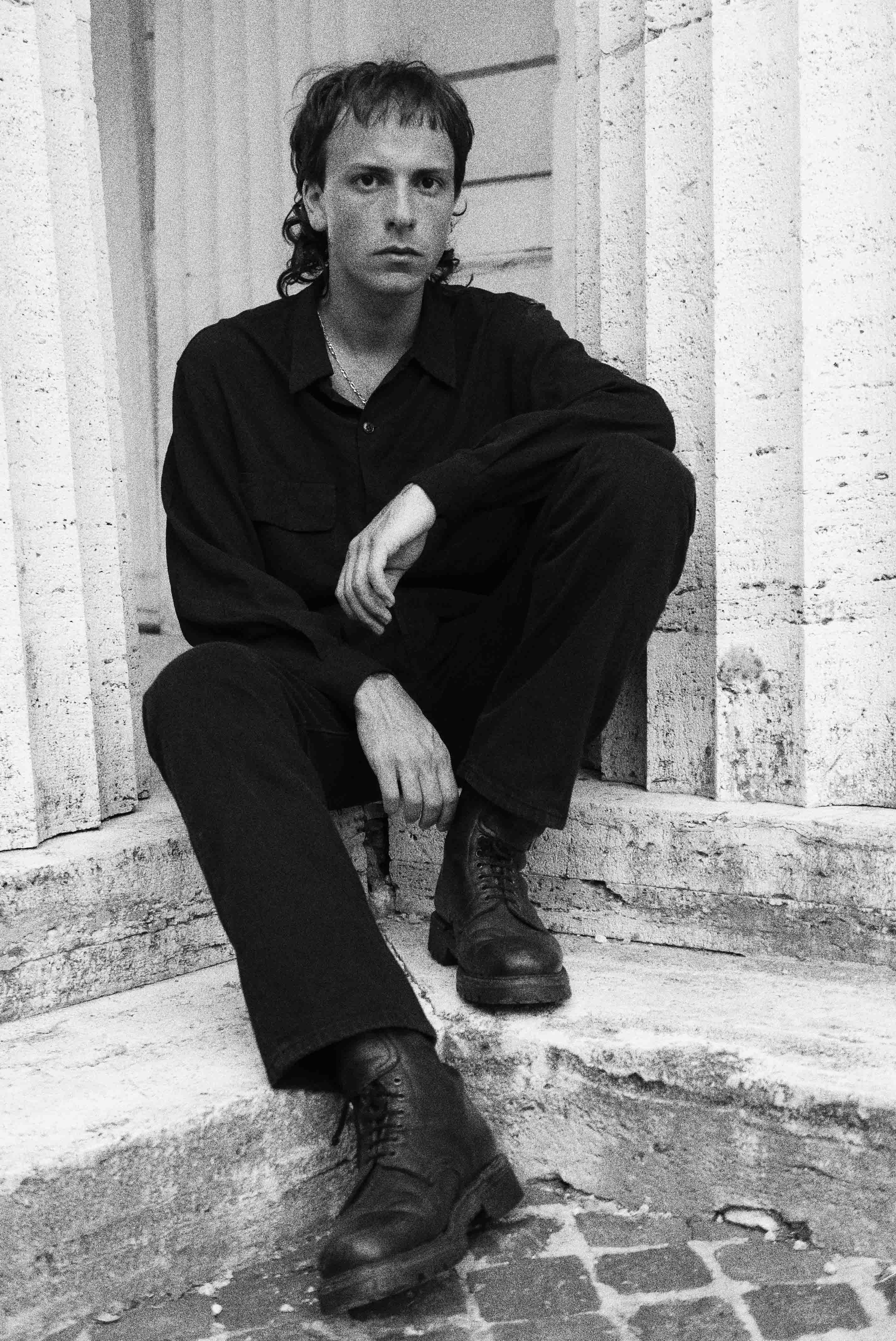un tizio seduto su scalini vestito di nero