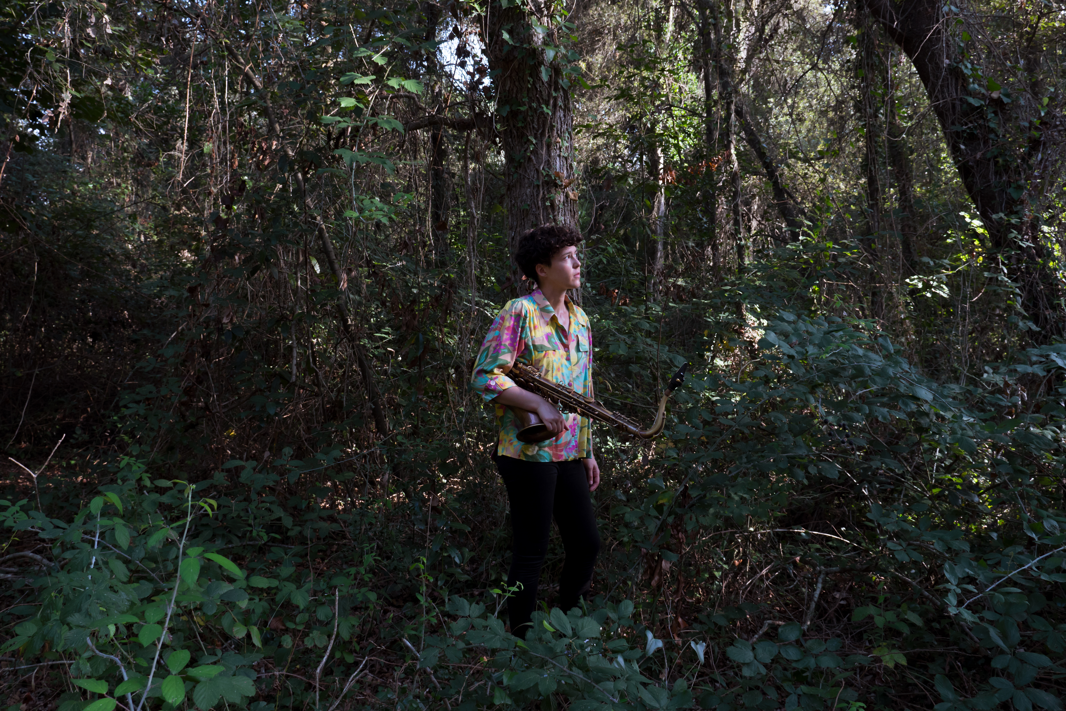 una persona con un sassofono in mezzo a un bosco