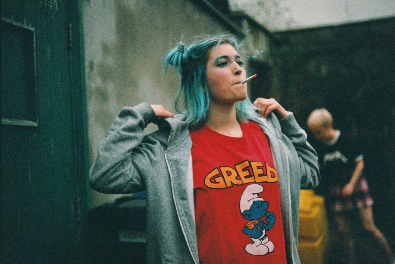 ragazza con capelli azzurri che fuma con indosso una maglietta rossa dei puffi
