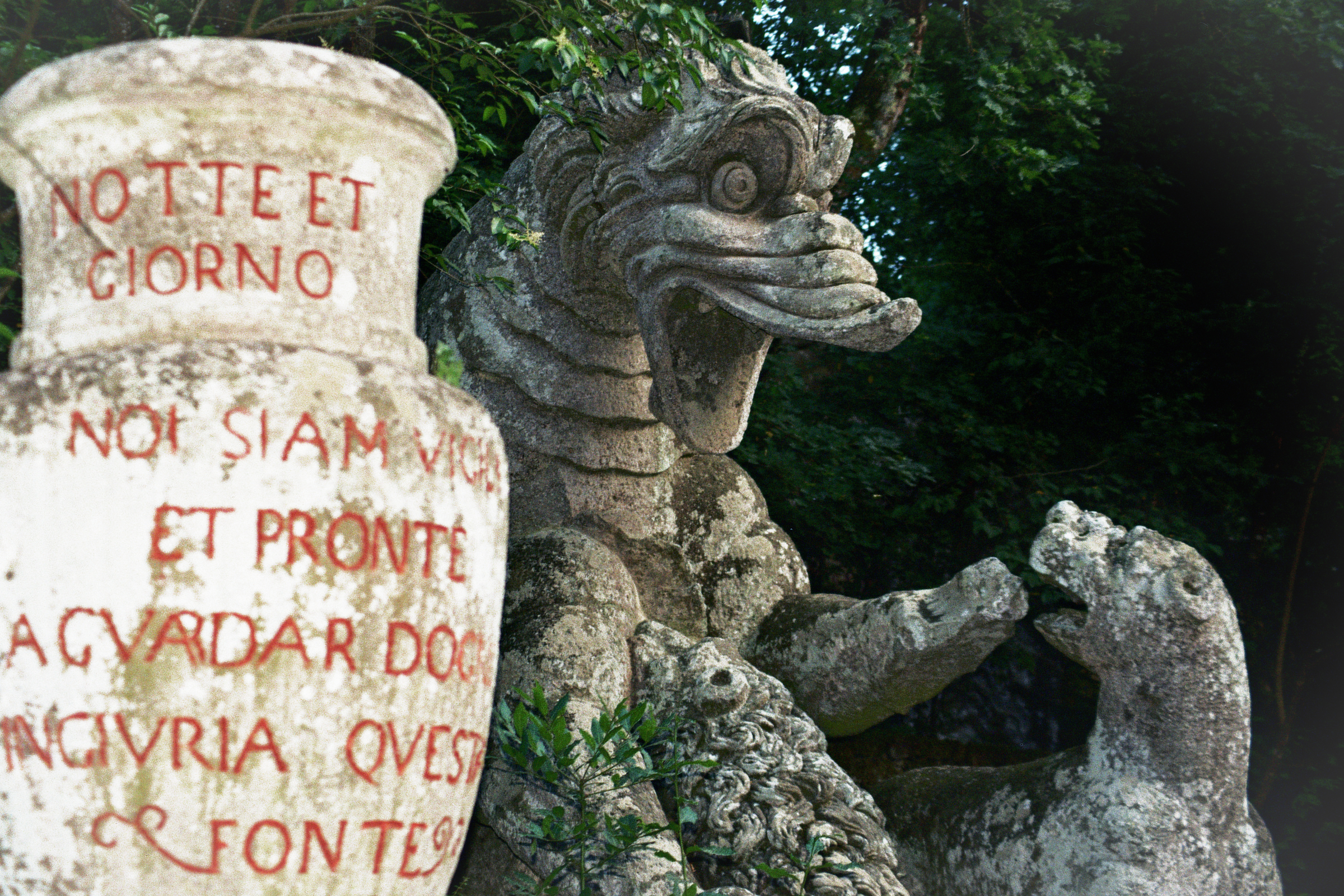 statua di essere mitologico con un vaso di pietra con scritte rosse
