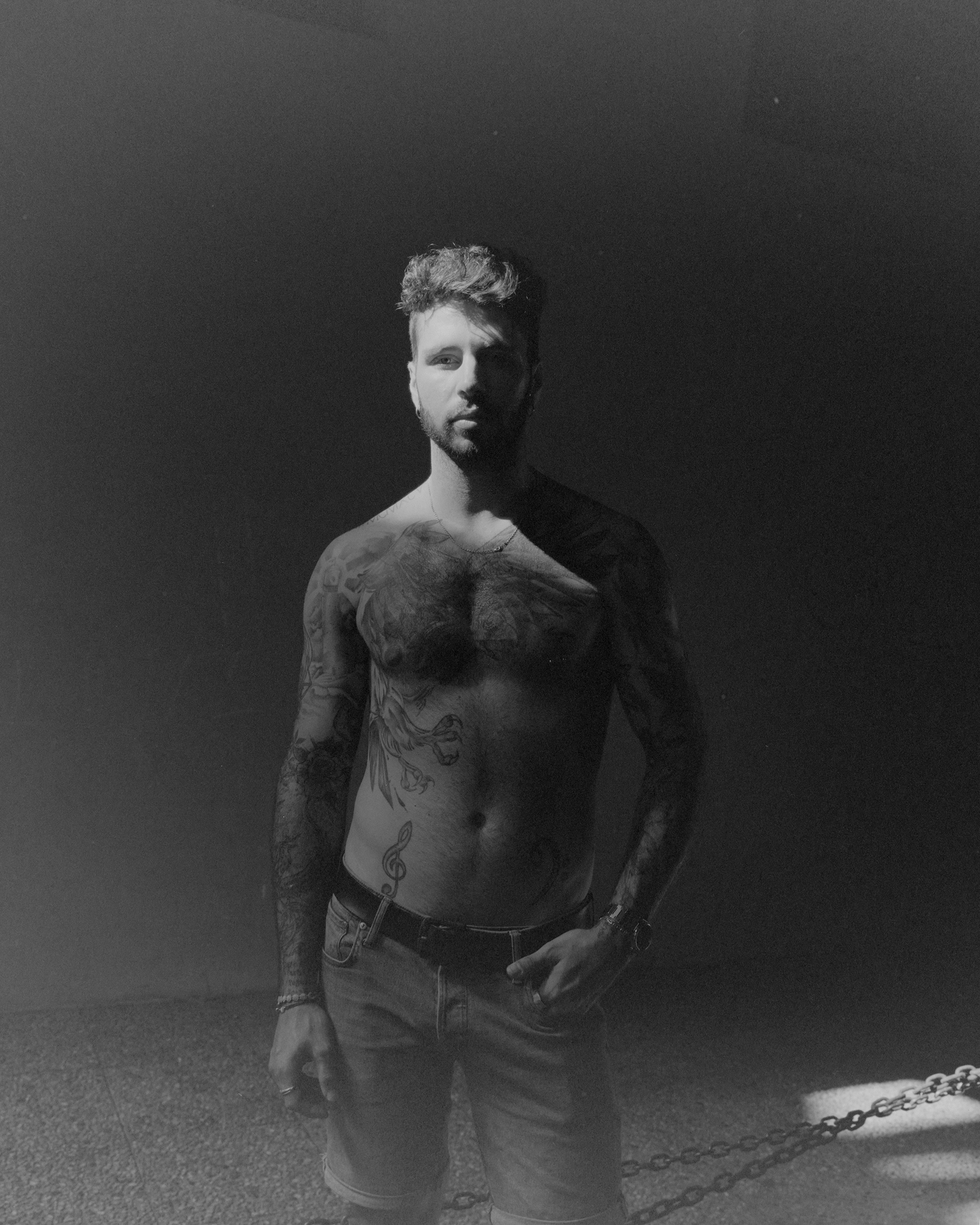 ragazo a torso nudo con tatuaggi foto in bianco e nero