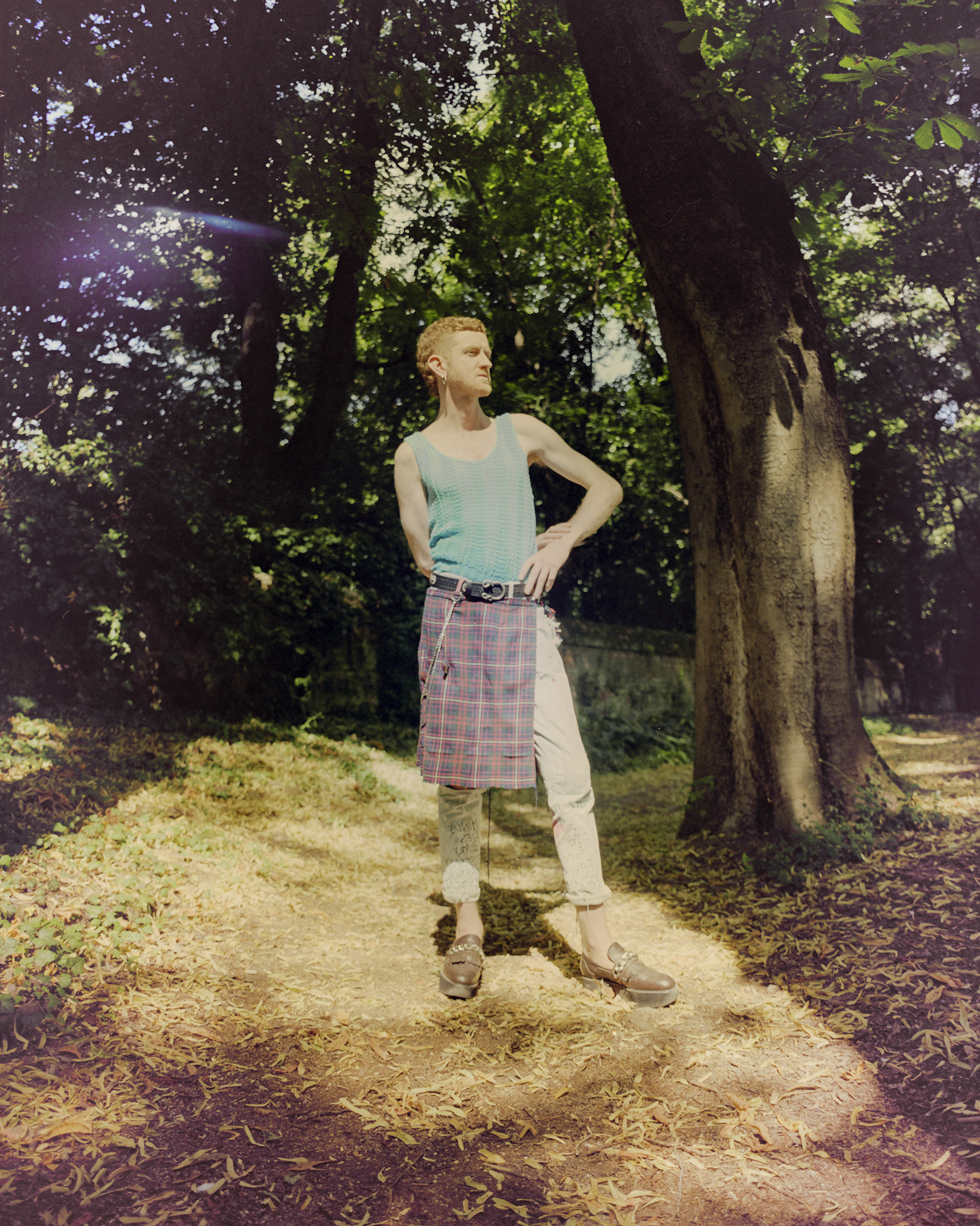 ragazzo in mezzo a un bosc con kilt e pantaloni jeans