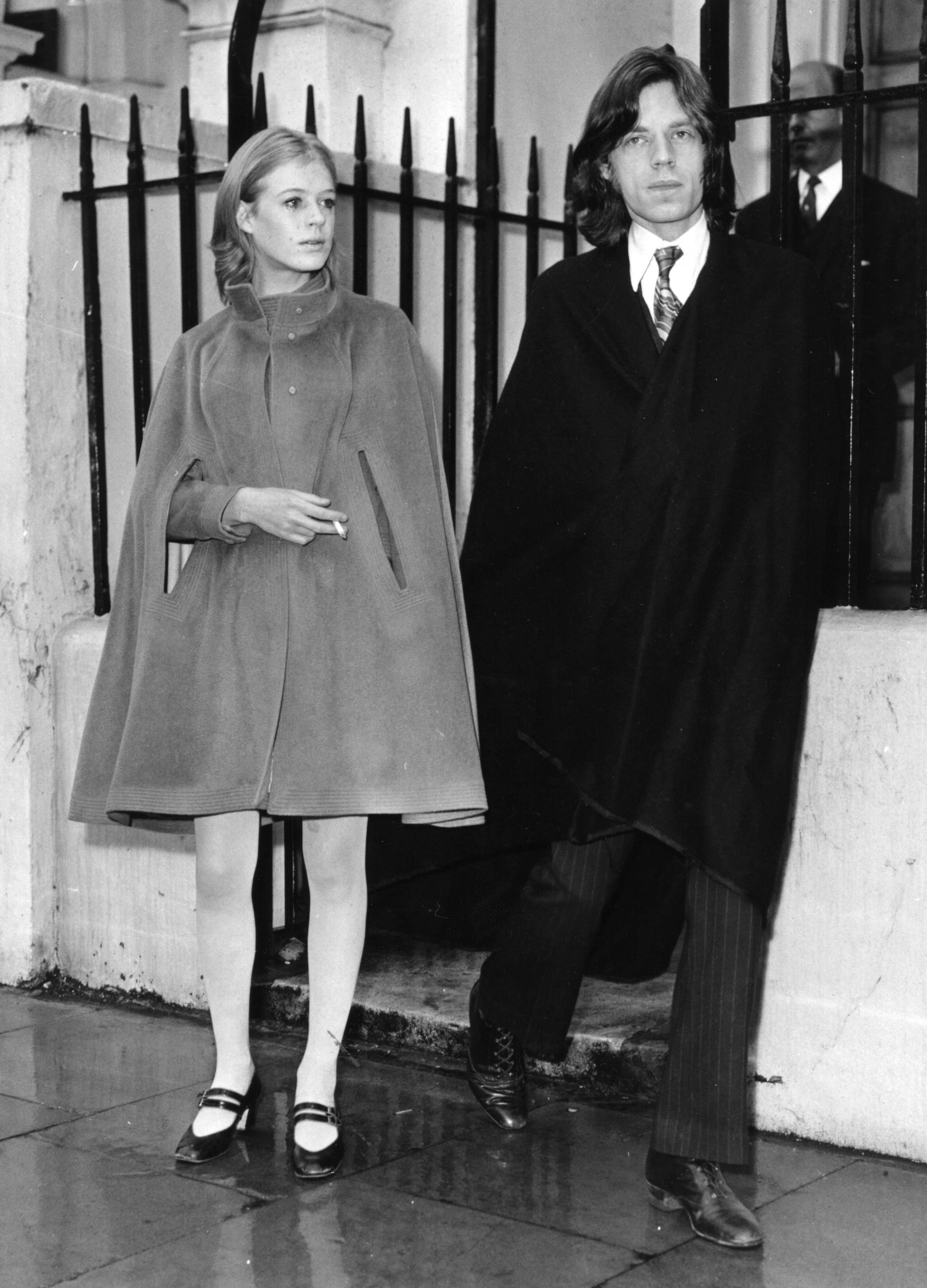 mick jagger and marianne faithfull walking on the sidewalk outside a courthouse in 1969