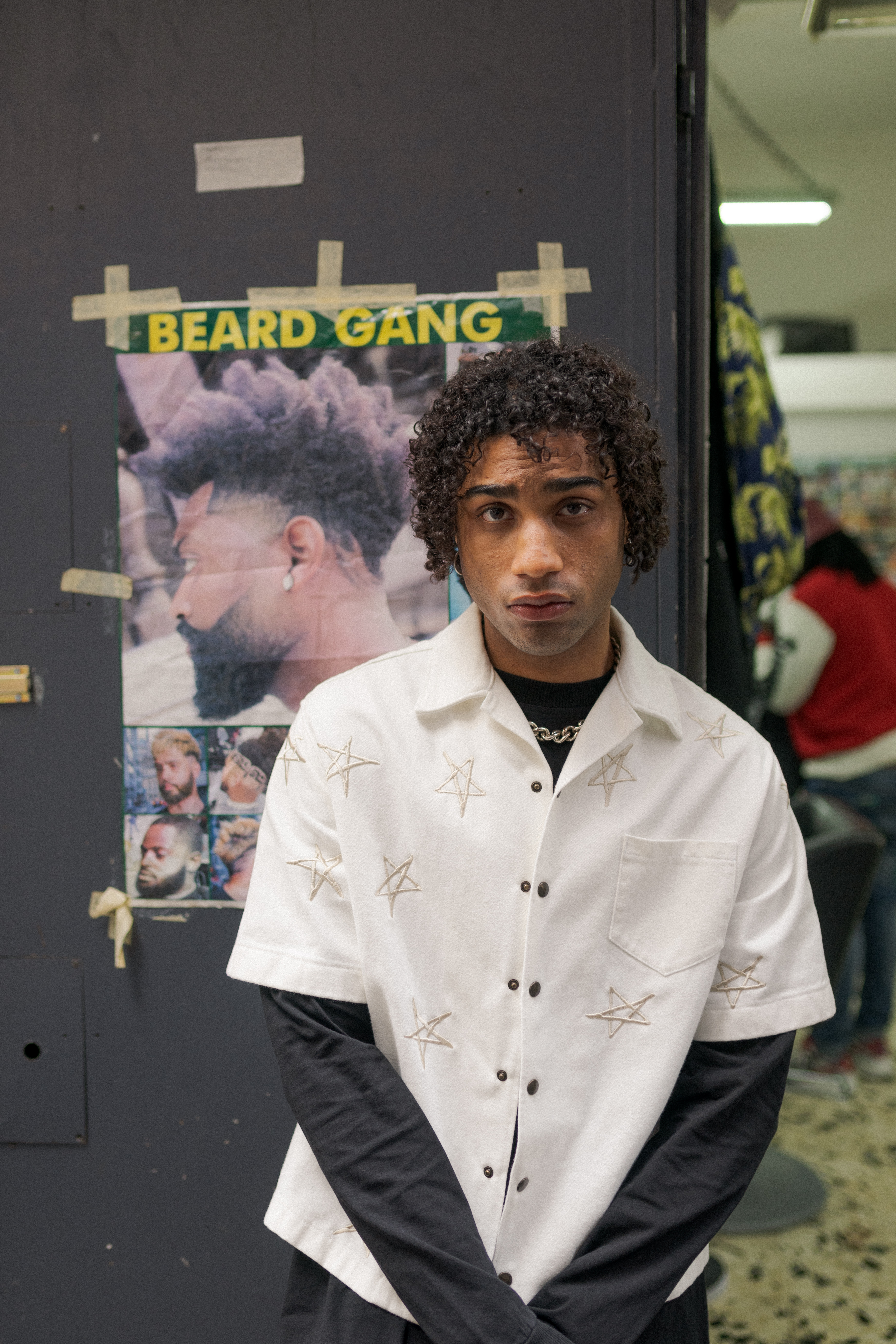 ragazzo afrodiscendente davanti al poster di un barbiere