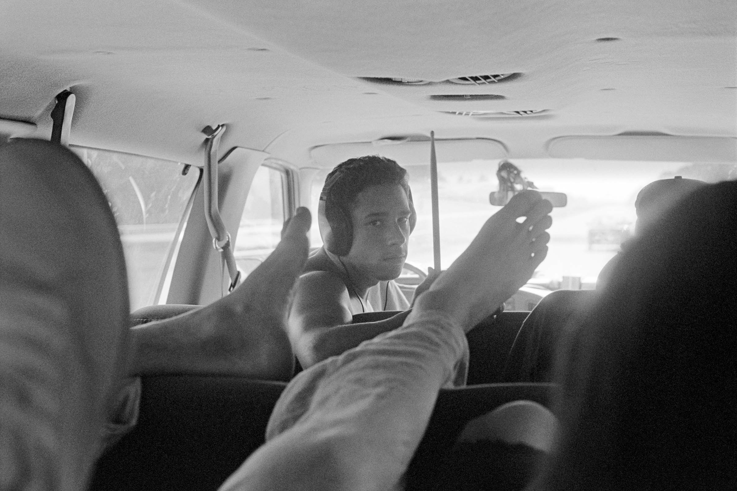 a man with headphones on in a van, framed by someone's feet