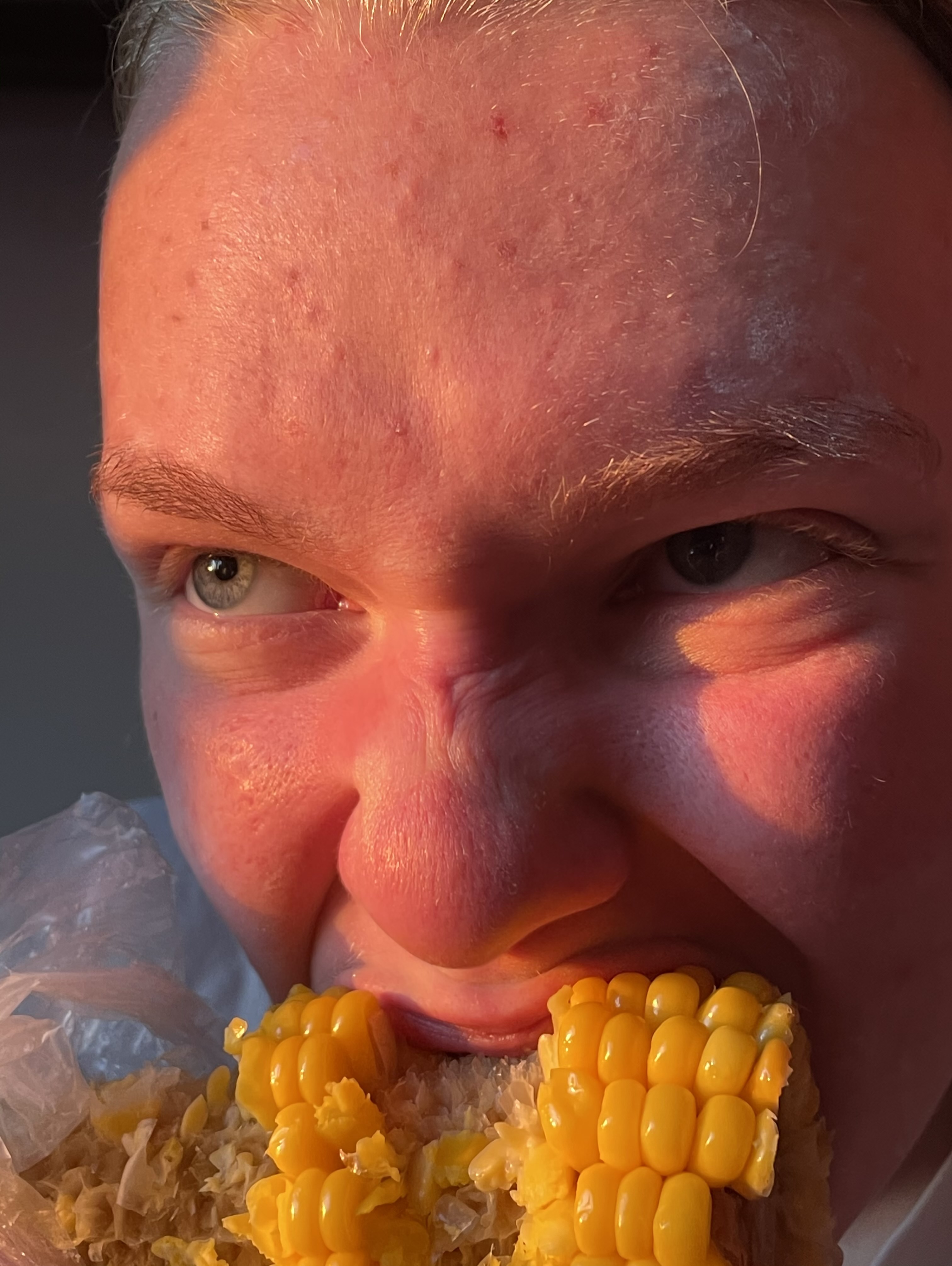 Close up of someone biting into a corn on the cob.