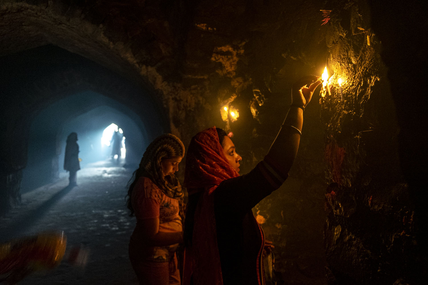 Dua perempuan menyalakan lilin di lorong