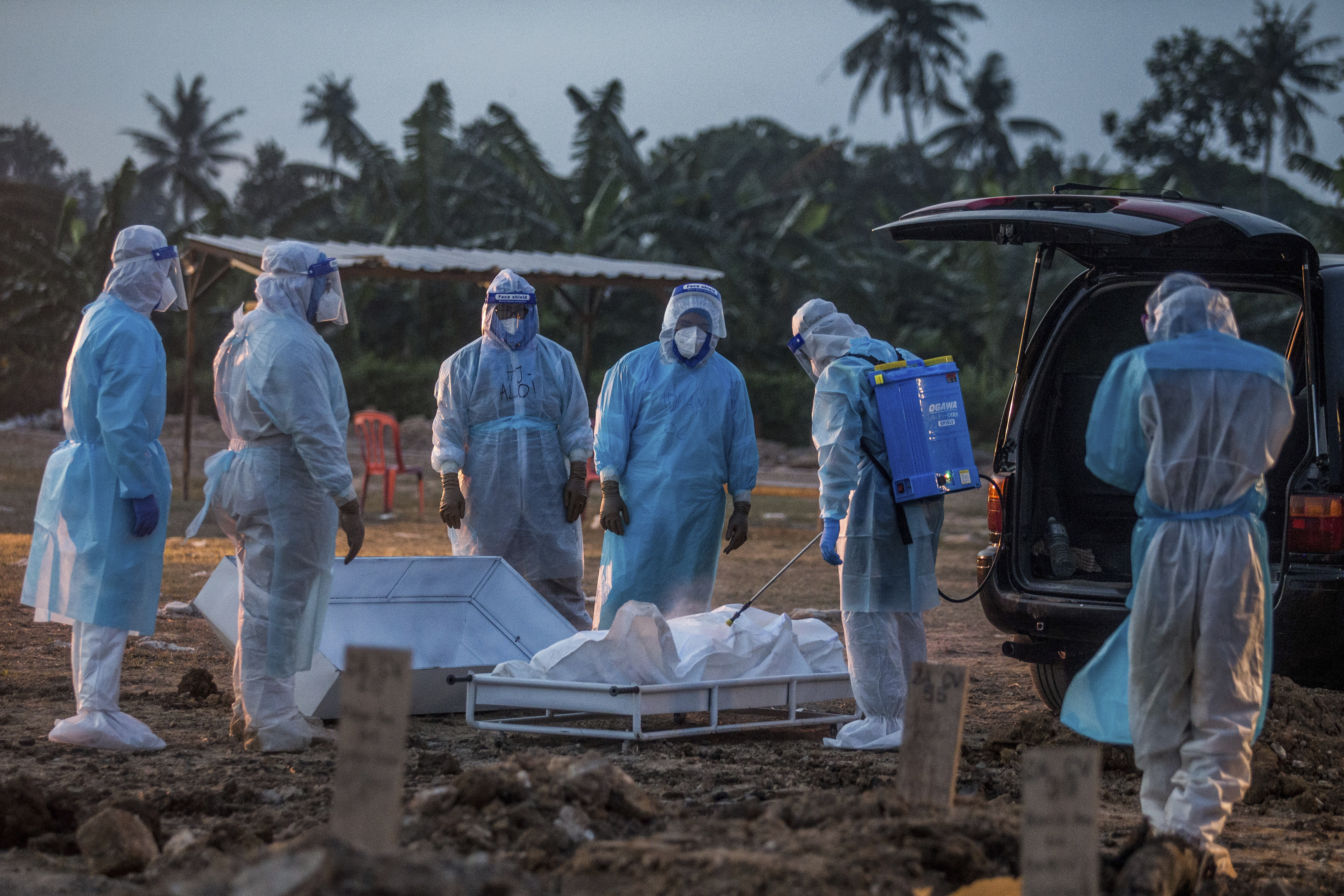 Health workers during a burial of COVID-19 victims in Klang, Malaysia. Photo by Zahim Mohd / AP
