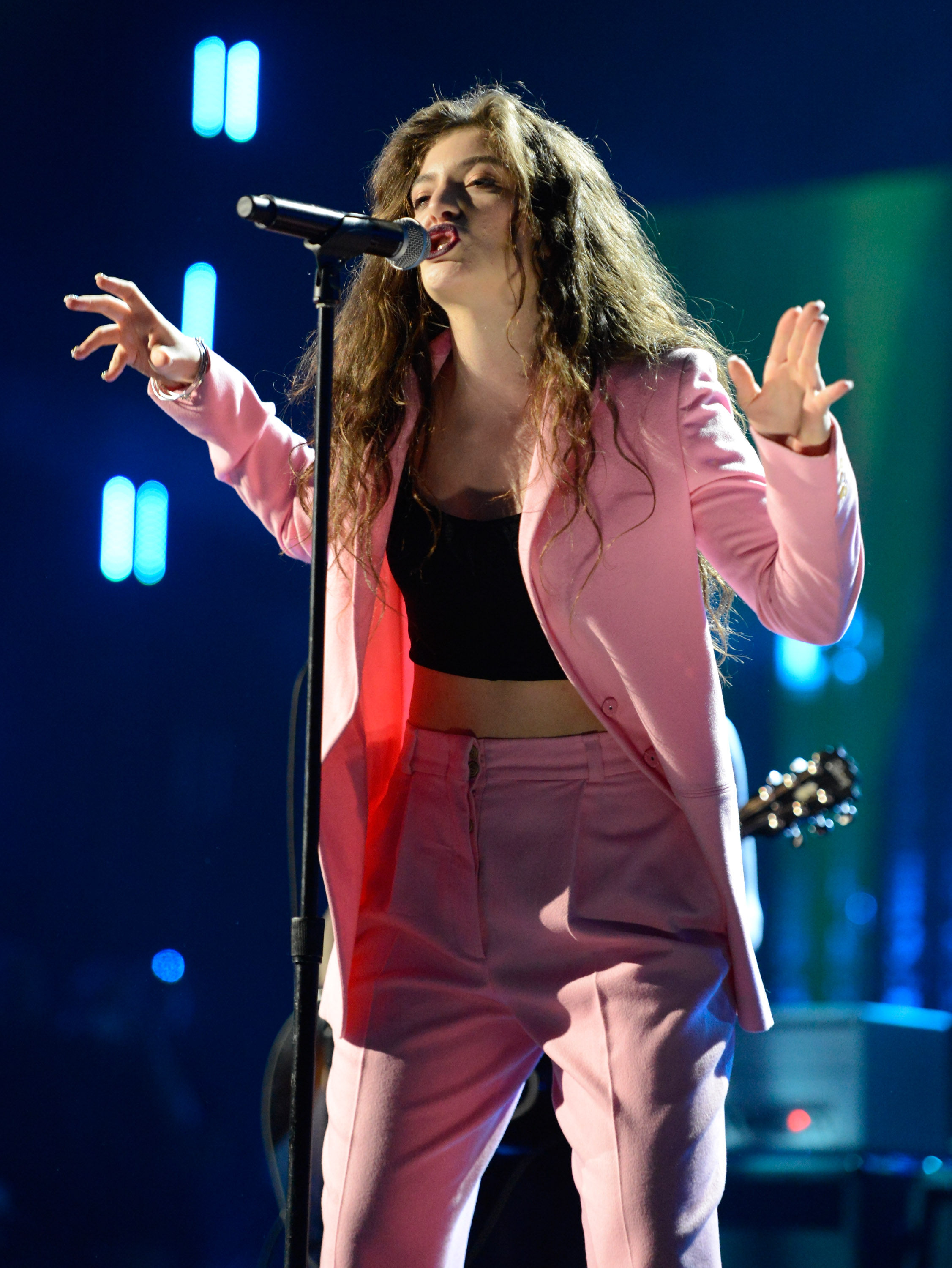 lorde singing into a microphone wearing a pink suit 2014