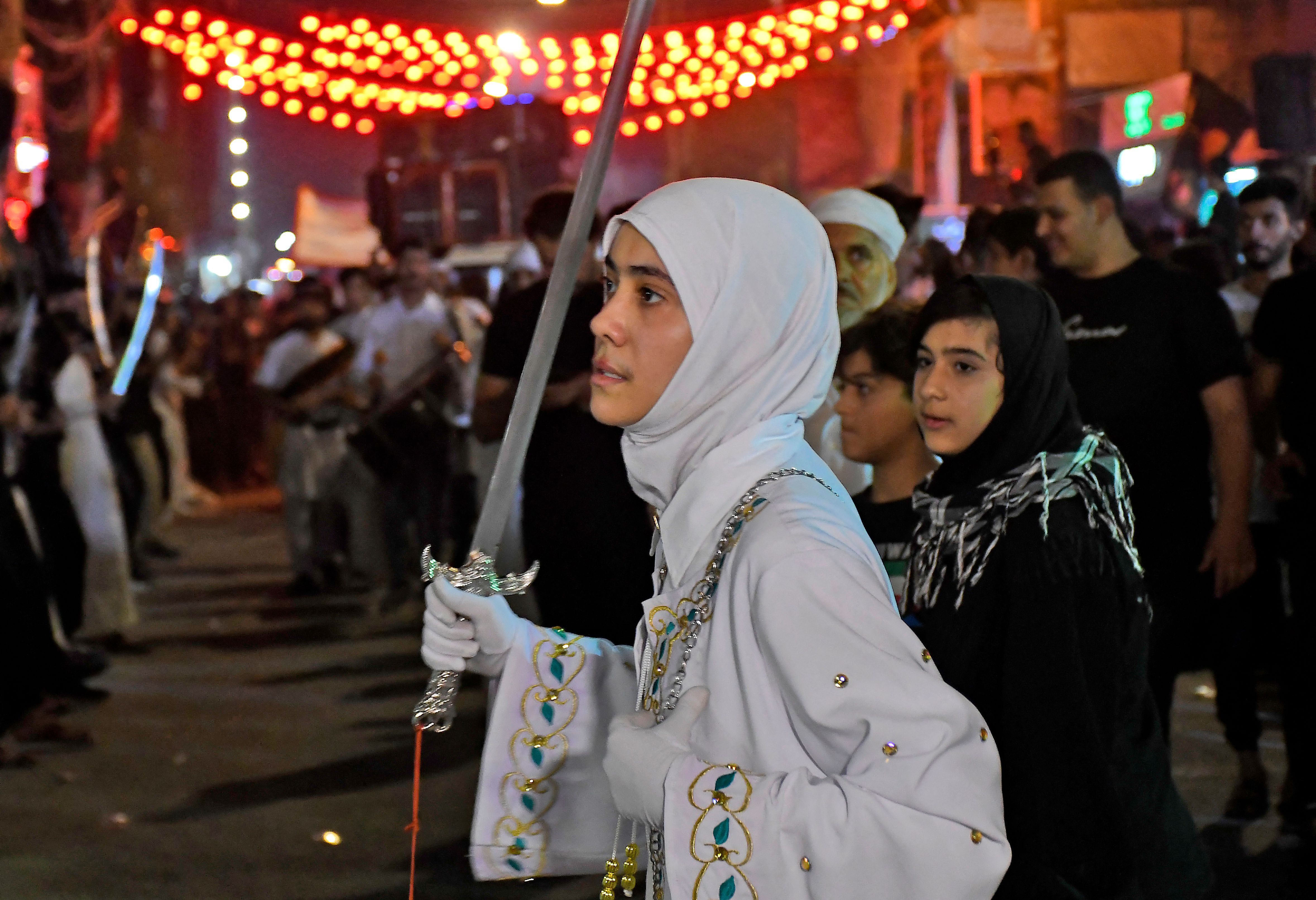 Perempuan mengangkat pedang di upacara berkabung yang digelar di Nasiriyah. Foto: Asaad Niazi/AFP via Getty Images