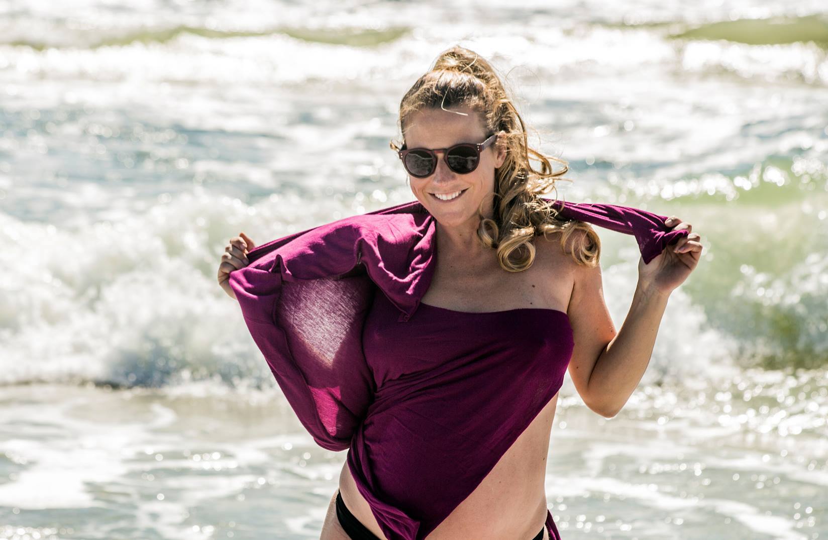 Perempuan mengenakan kacamata dan kaus ungu di pantai