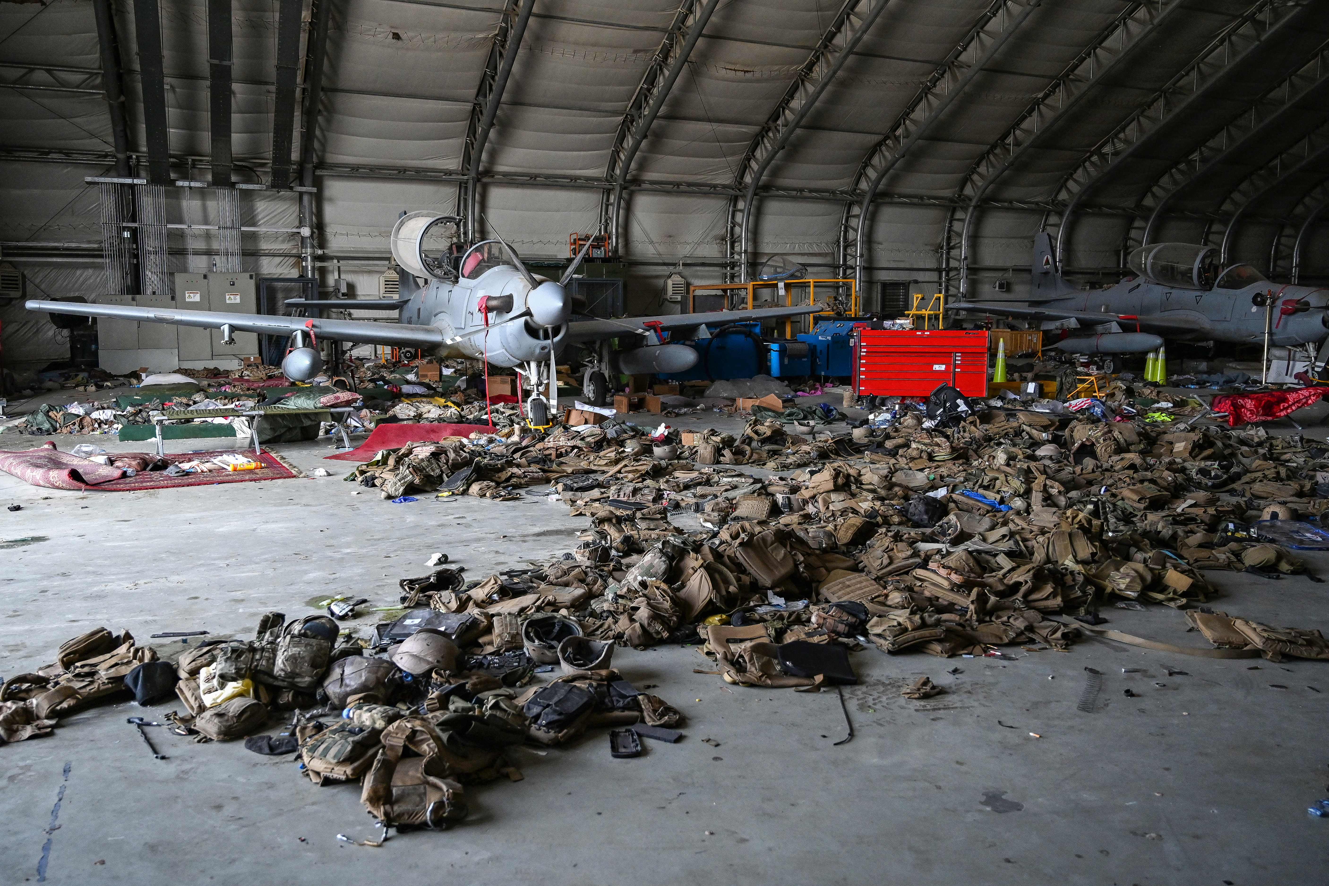 Pesawat serang Angkatan Udara Afghanistan diistirahatkan di hanggar bandara Kabul. Tumpukan rompi militer tersebar di sekitarnya. Foto oleh Wakil Kohsar/AFP via Getty Images