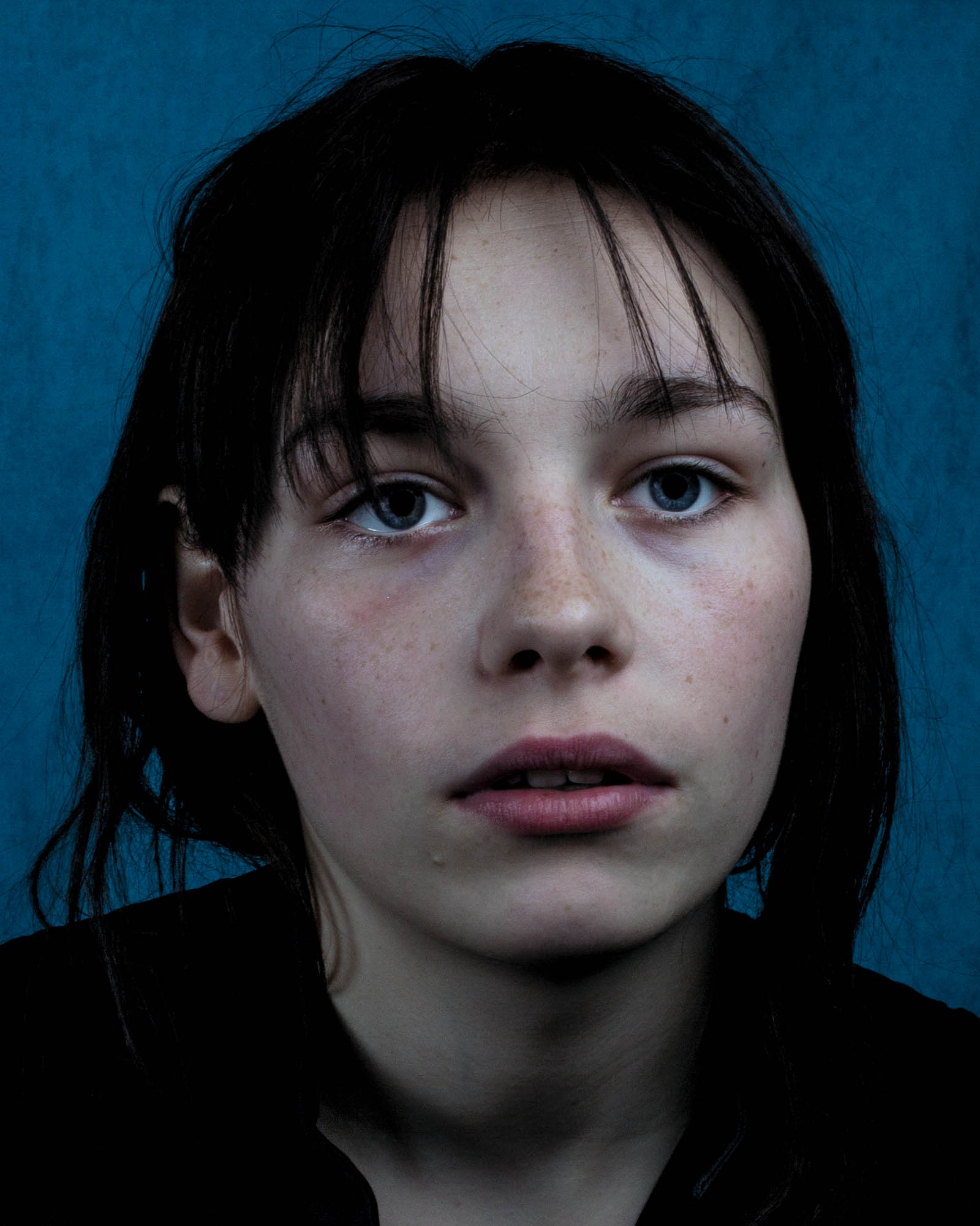 a portrait of a young woman's face against a blue backdrop