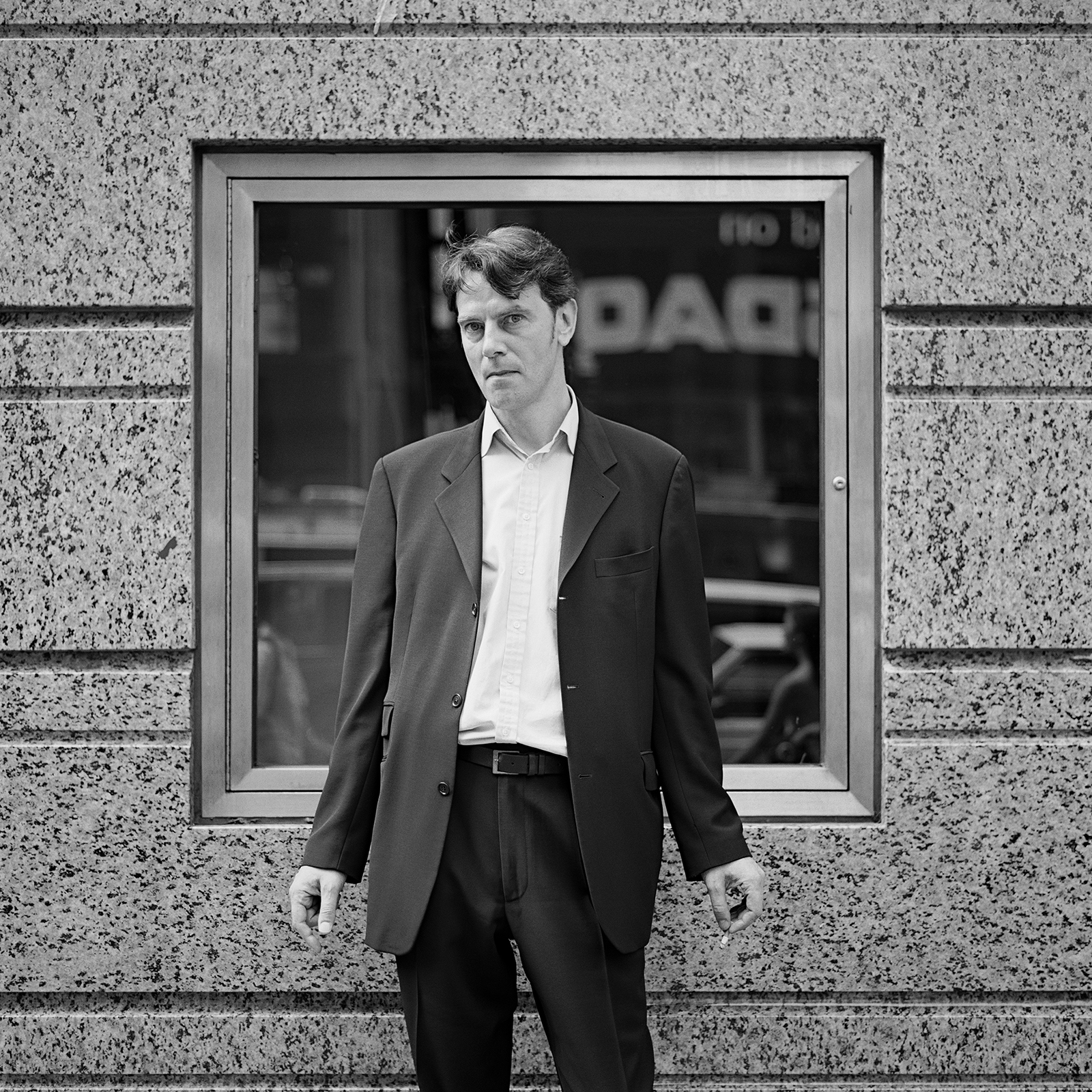 a man in a suit smoking a cigarette on the street