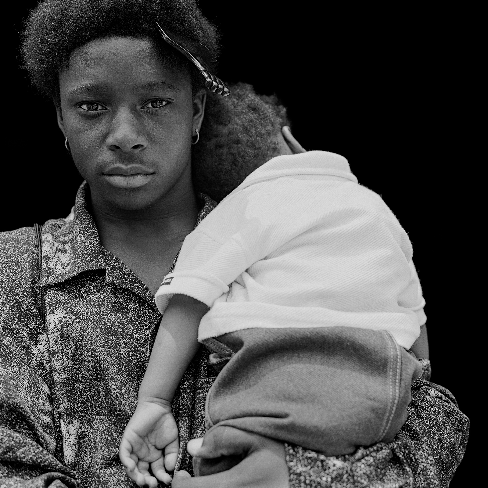 a young man with a comb in his hair holds a baby in his arms