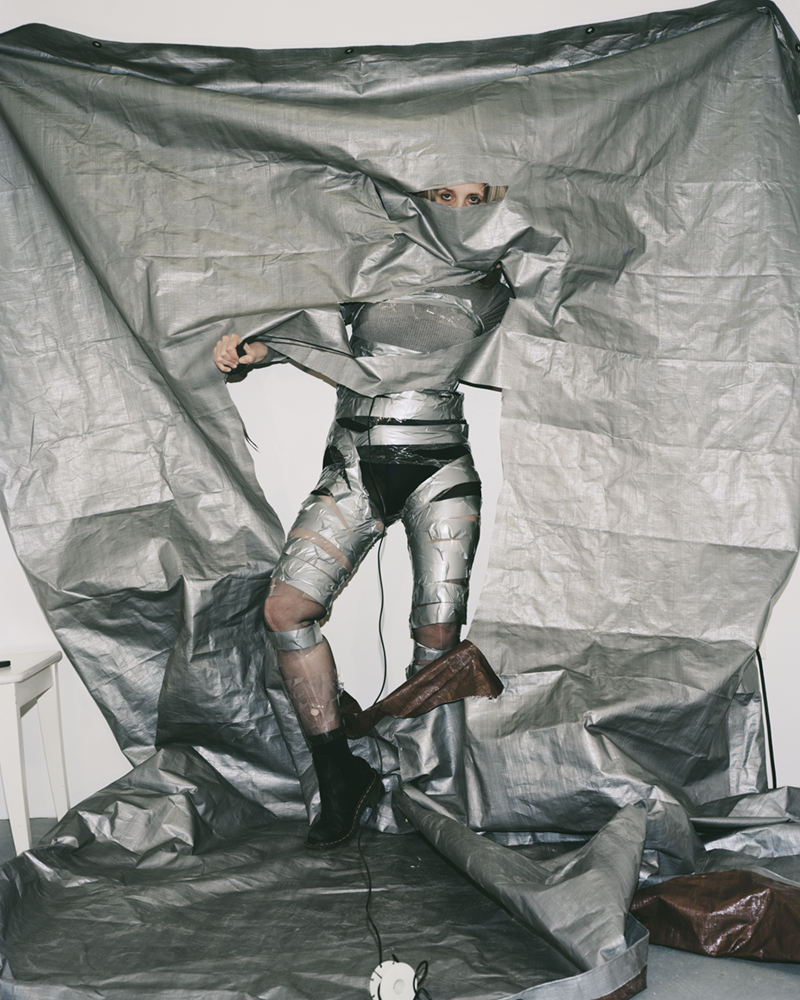 a woman taped to a wall with grey tape