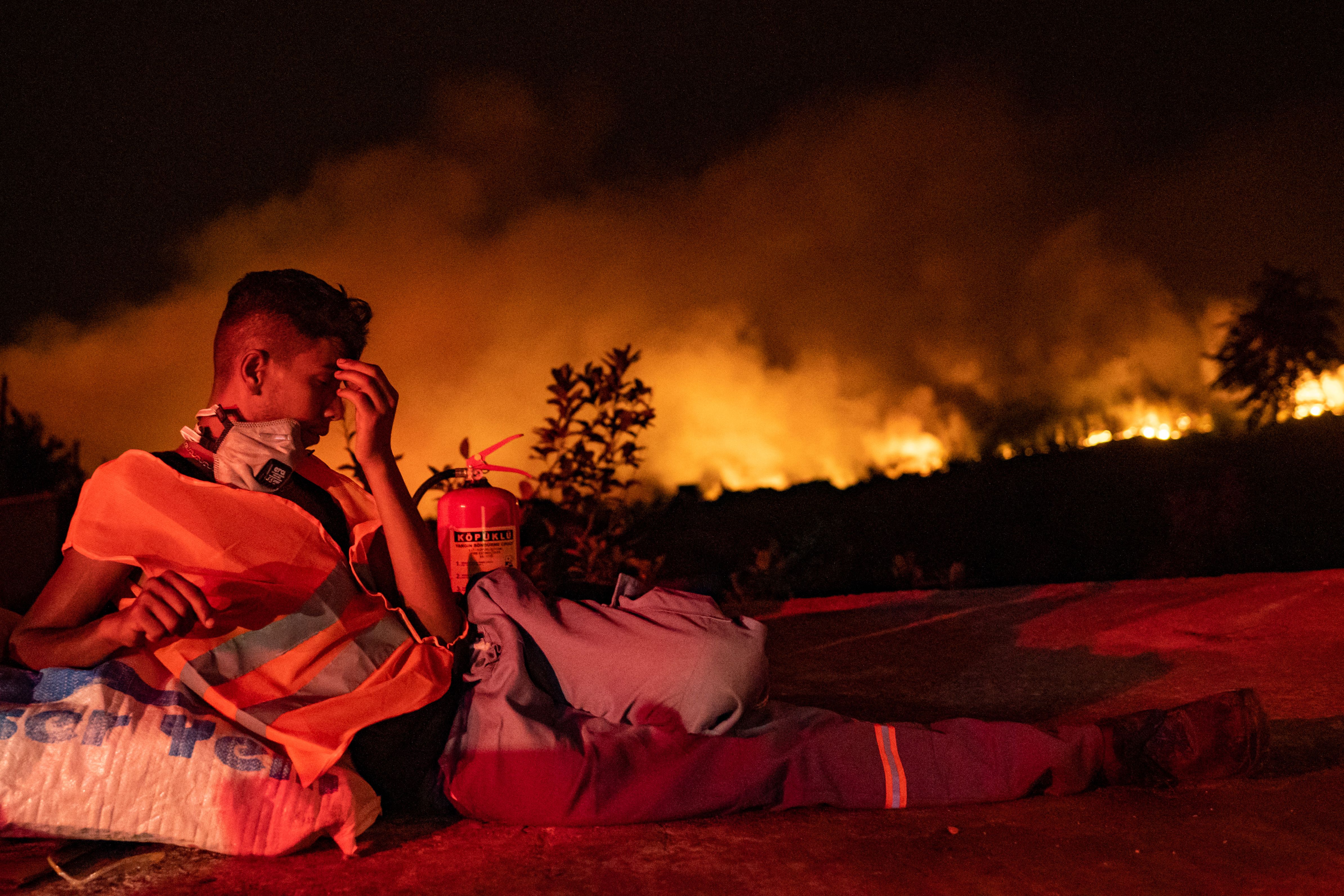Sukarelawan beristirahat di tengah kobaran api yang melahap hutan provinsi Mugla di Turki bulan lalu. Foto: Yasin Akgul/AFP via Getty Images