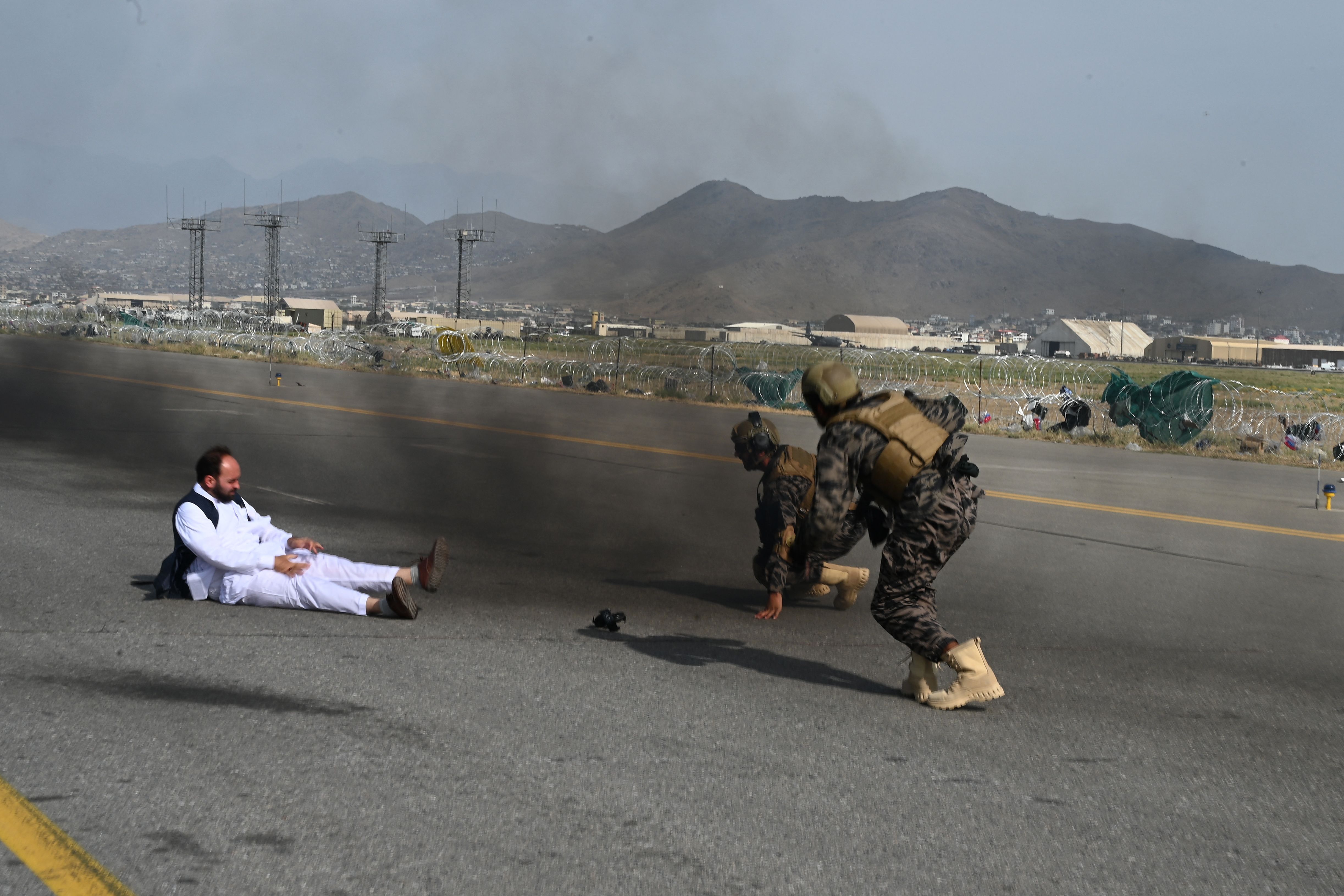 Dua prajurit pasukan khusus Badri Taliban dan seorang jurnalis berdiri setelah terjatuh dari kendaraan di bandara Kabul pada akhir Agustus, setelah AS menarik pasukannya dari Afghanistan. Foto: Wakil Kohsar/AFP via Getty Images