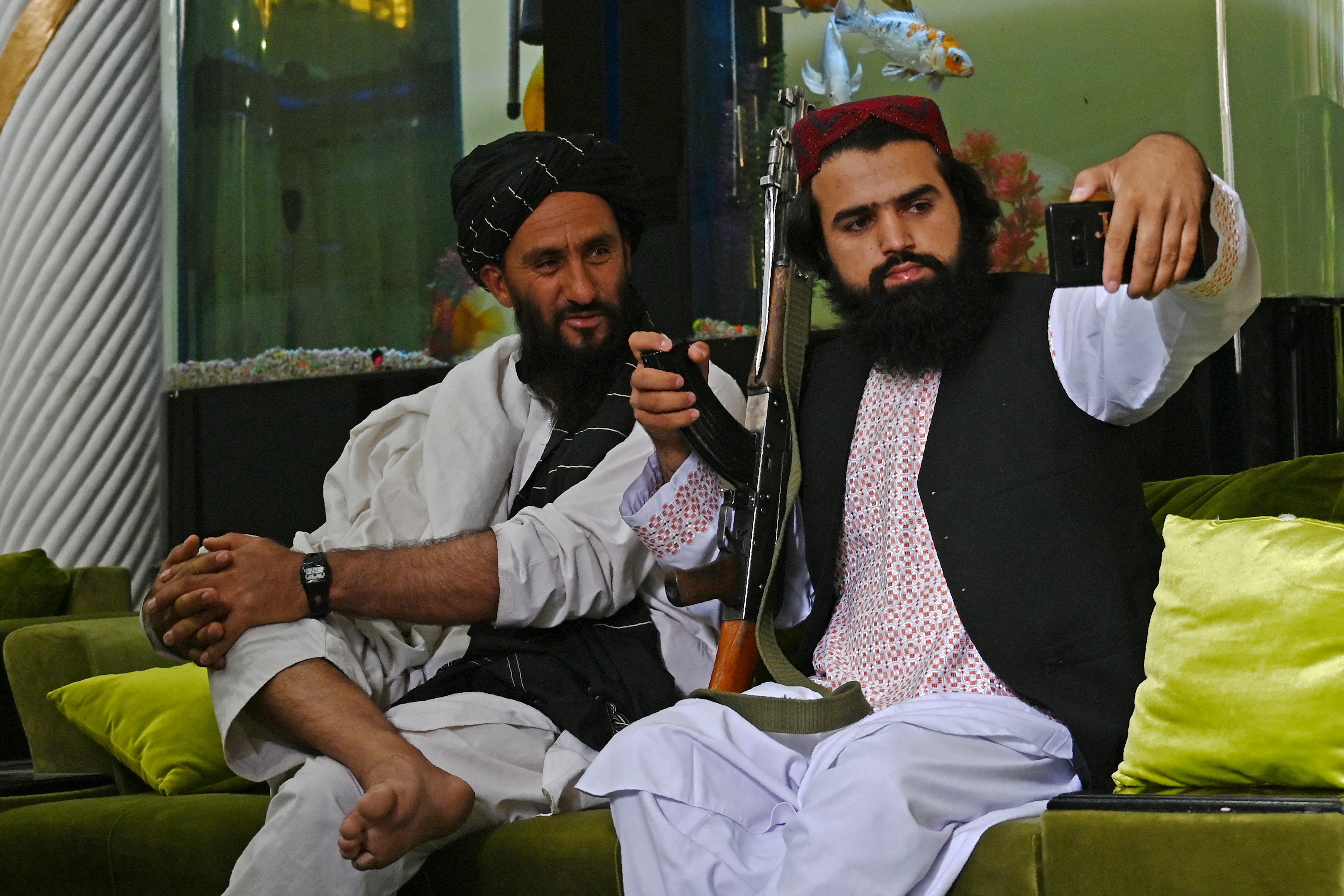 Dua prajurit Taliban selfie di depan akuarium milik panglima perang Abdul Rashid Dostum setelah mengambil alih rumahnya di Kabul. Foto: Wakil Kohsar/AFP via Getty Images