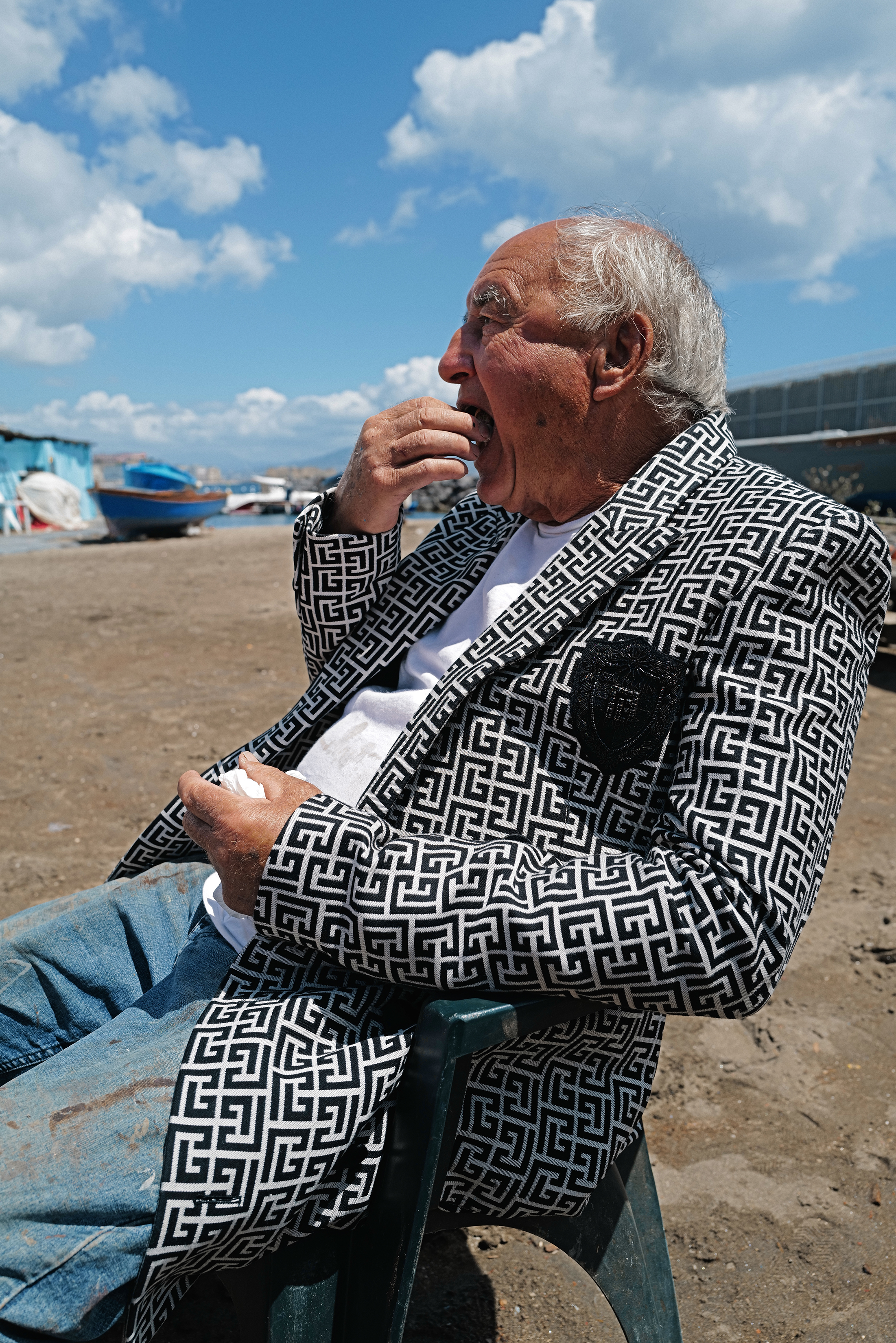 un uomo che mangia seduto su una sedia in spiaggia
