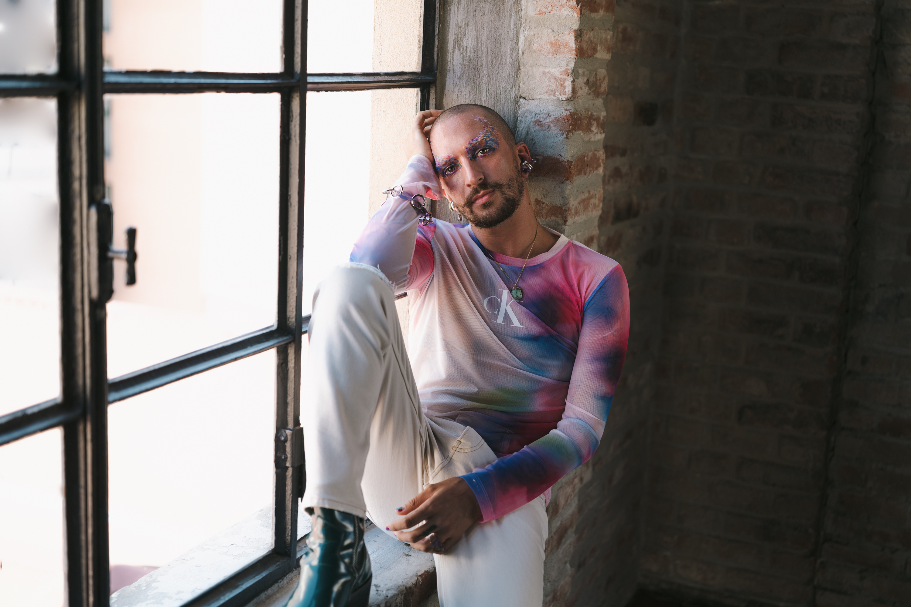 venerus seduto su una finestra con indosso maglia calvin klein