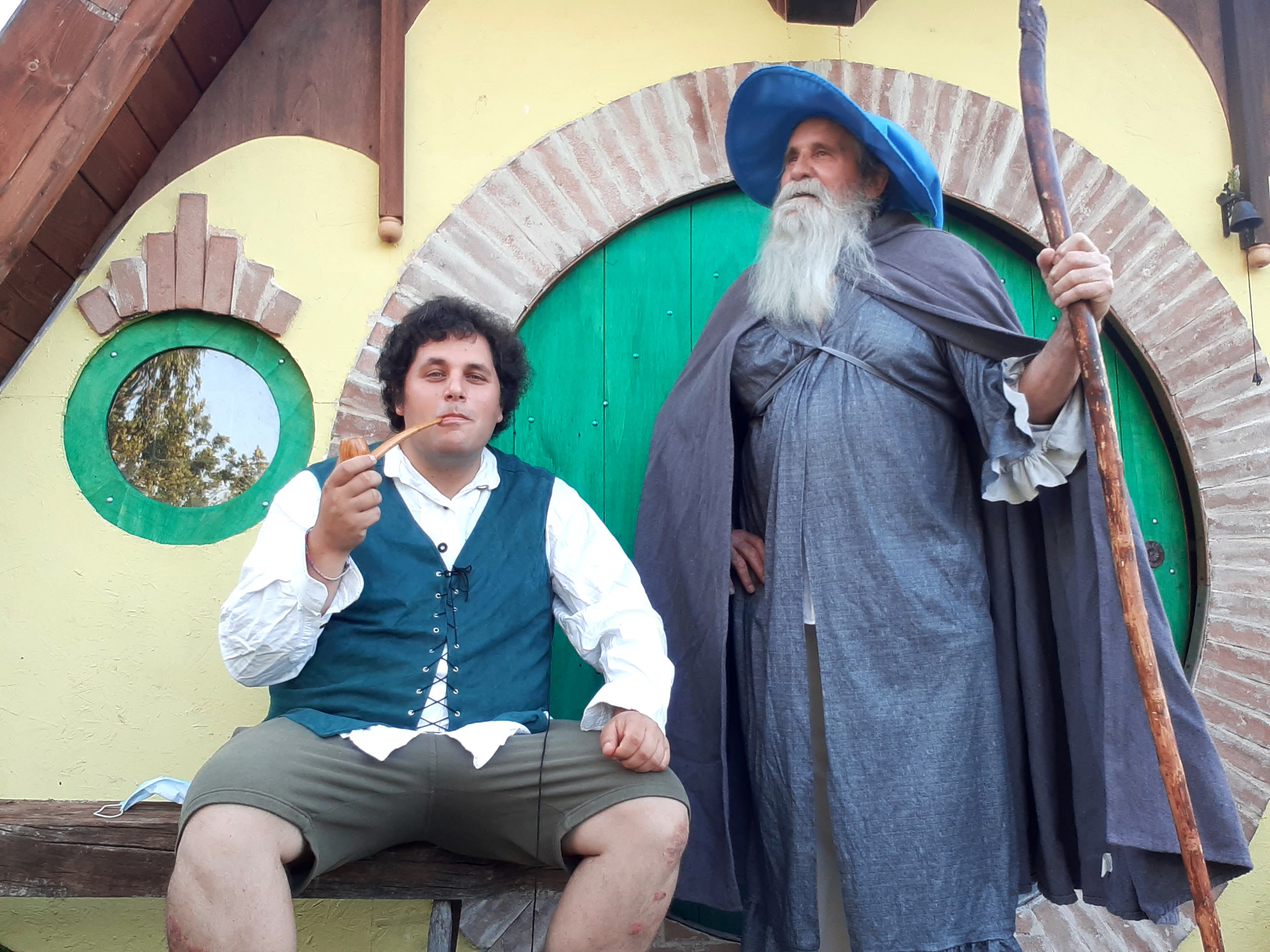 Lelaki berpakaian ala Hobbit berpose di sebelah karakter Gandalf berjanggut panjang