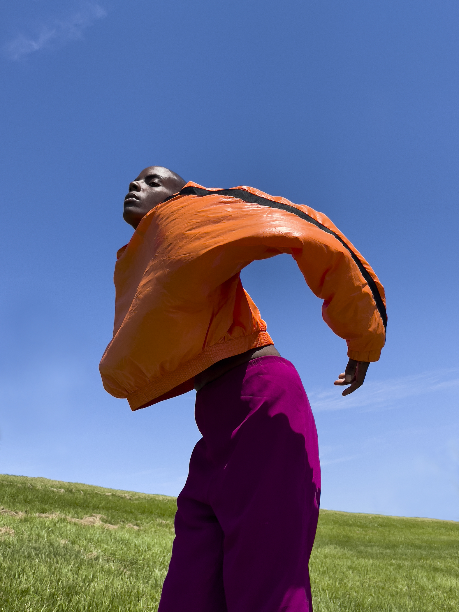 a portrait of a woman in a grassy field wearing bright colors by arielle bobb-willis