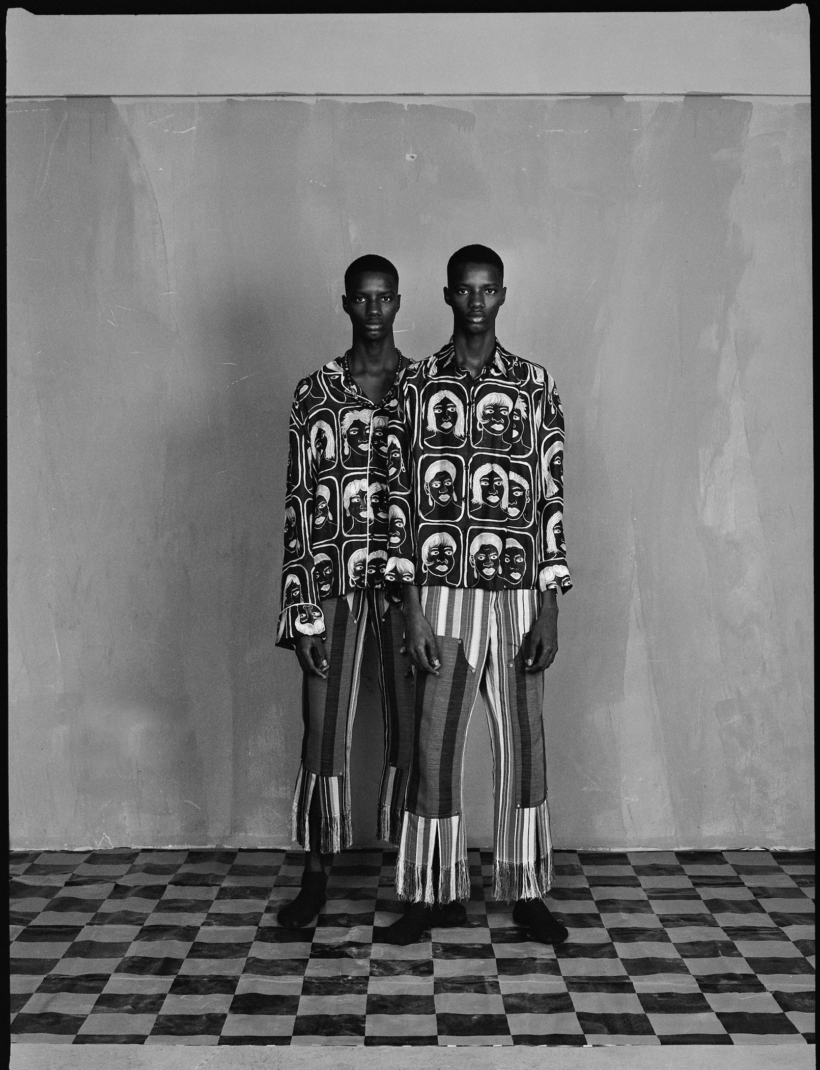 a portrait of two boys in printed west african clothes shot in black and white by brad ogbonna