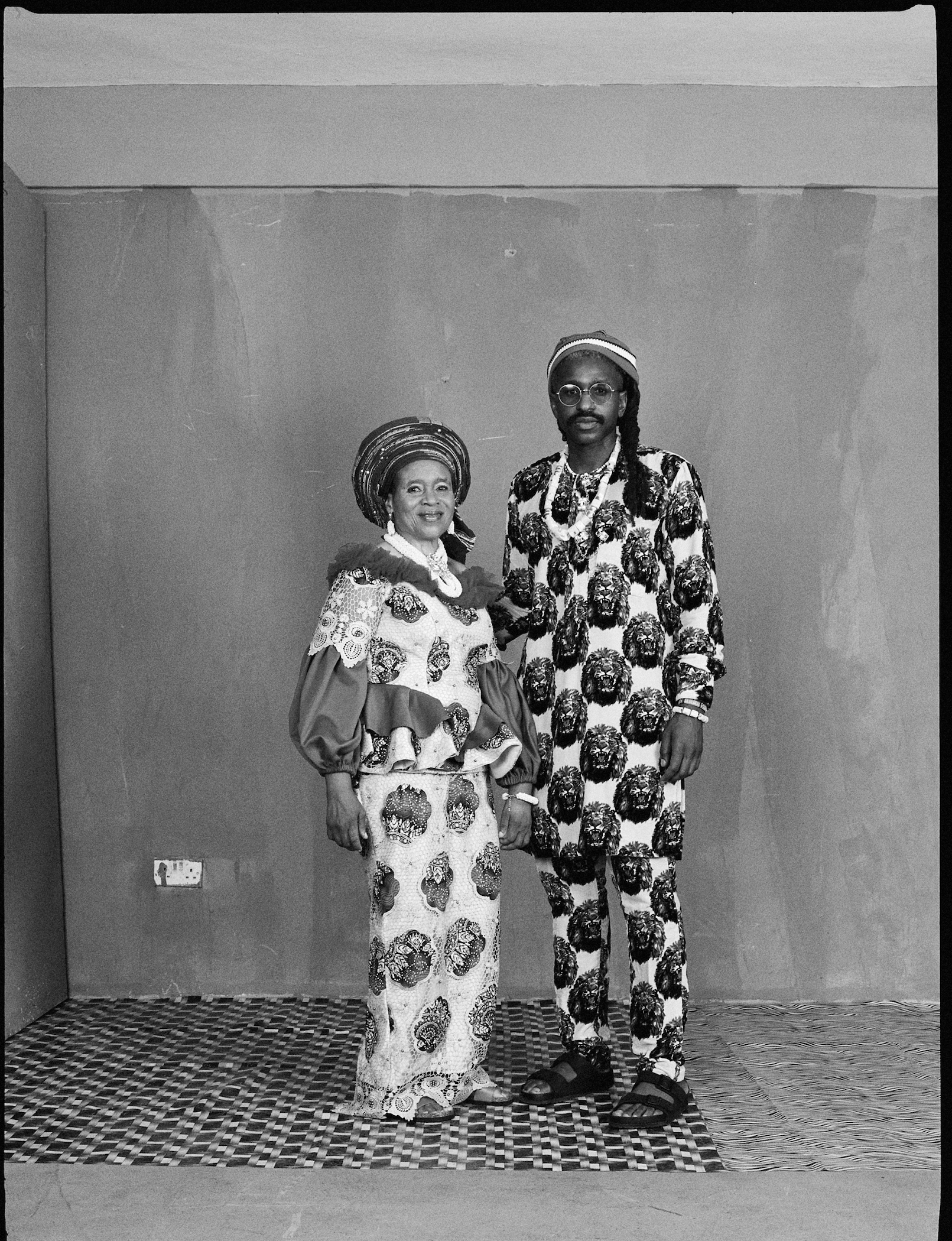 a portrait of two people in printed west african clothes shot in black and white by brad ogbonna