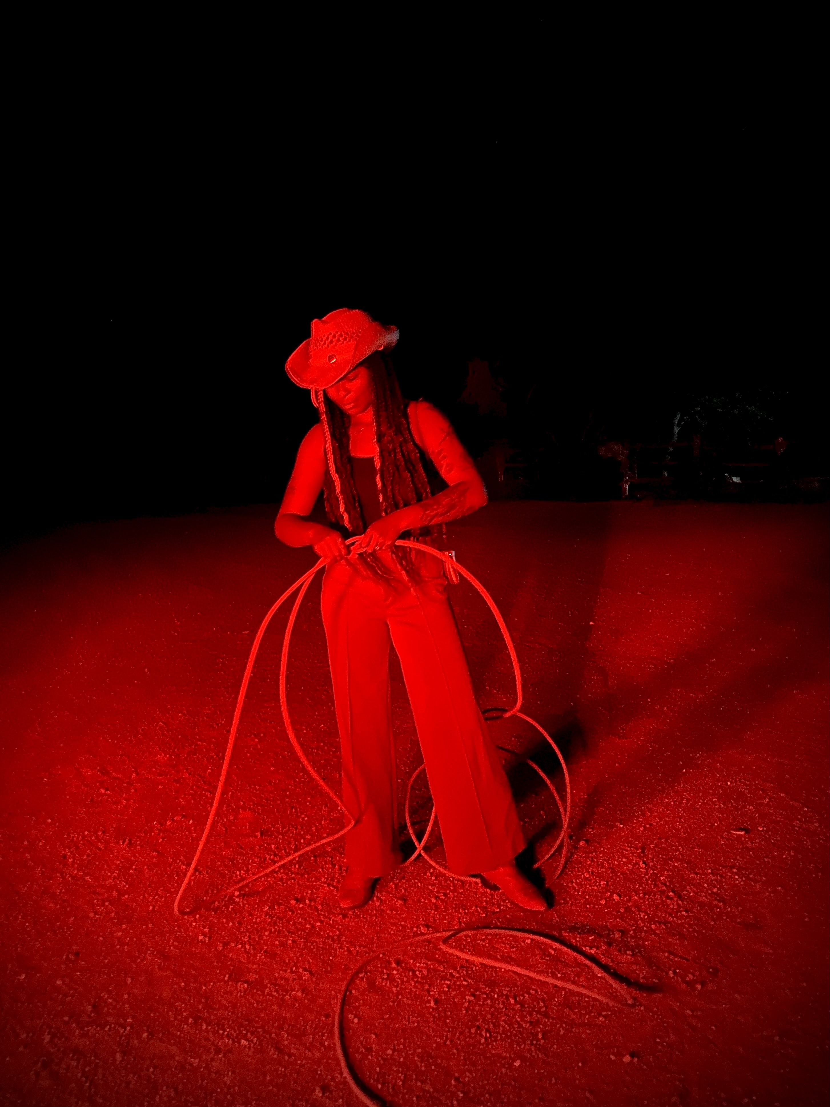Woman putting together a lasso outside under a red light.
