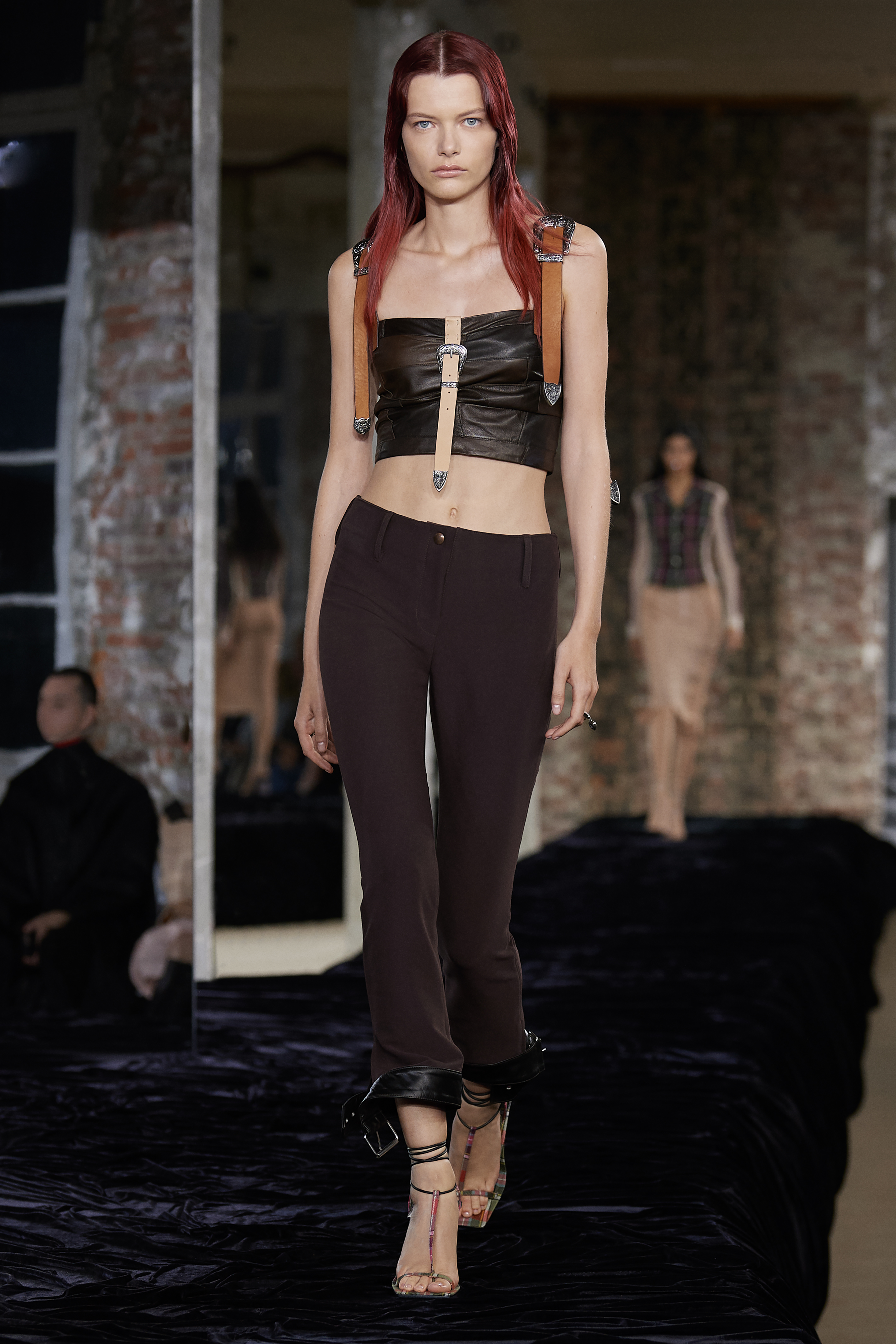 Acne Studios SS22: a model wears brown trousers with a brown patchwork leather bodice