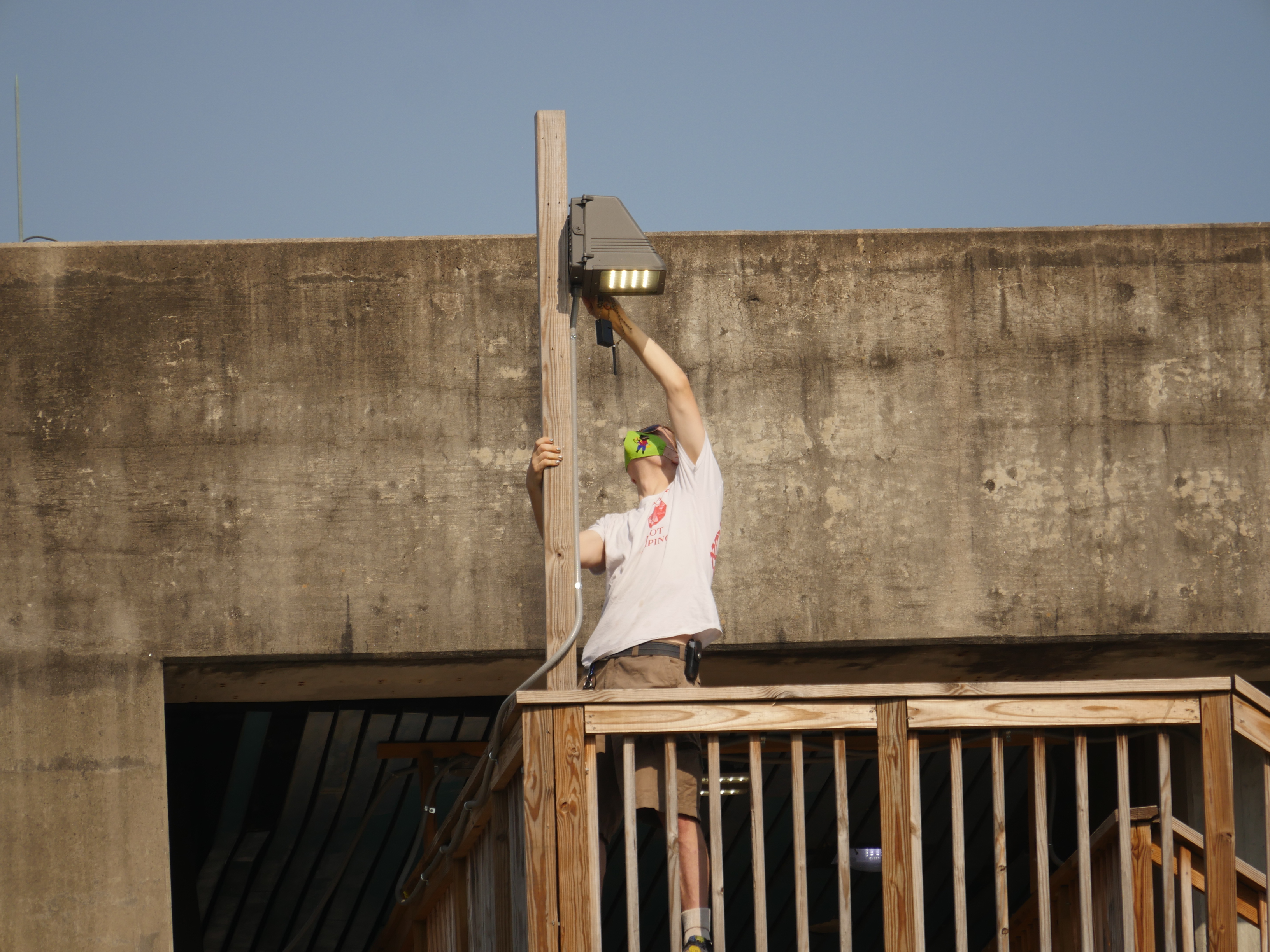 A volunteer affixes a mesh networking node to a light pole.