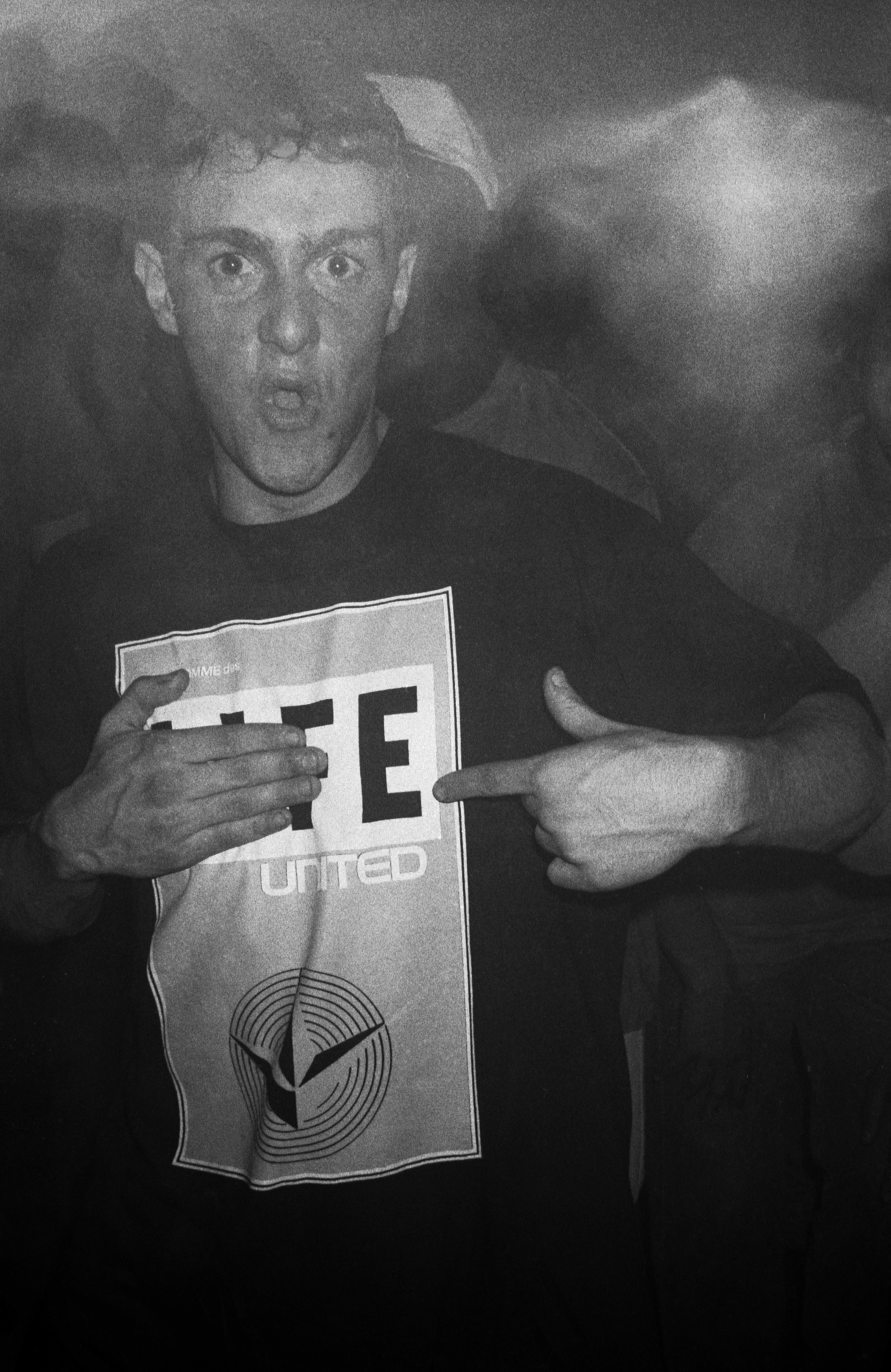 a man points to the E on his t-shirt