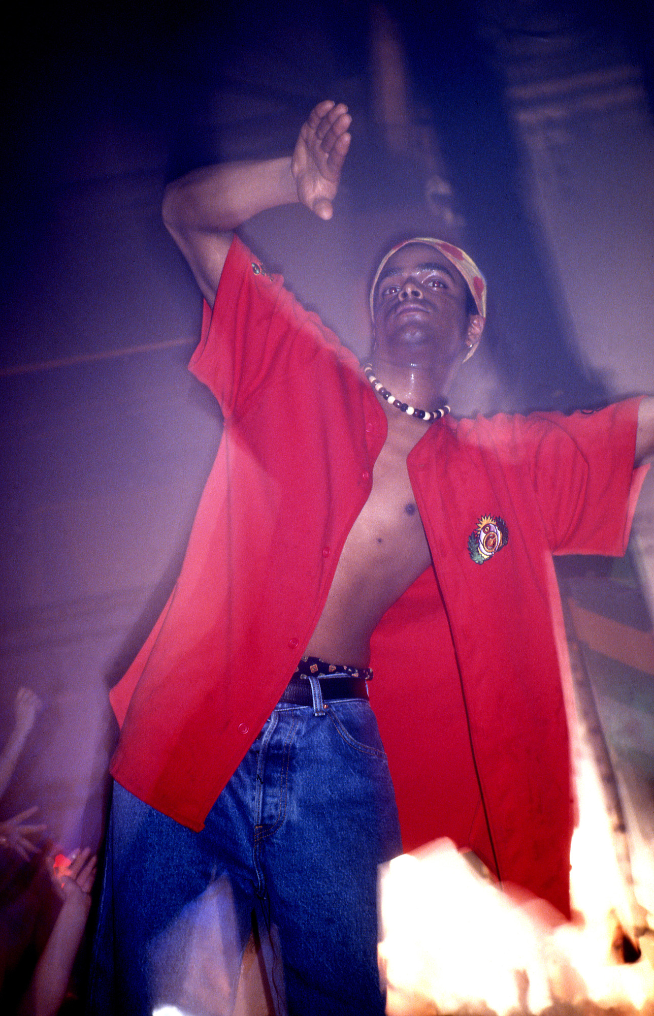 a sweaty man wearing an open shirt dancing in a club