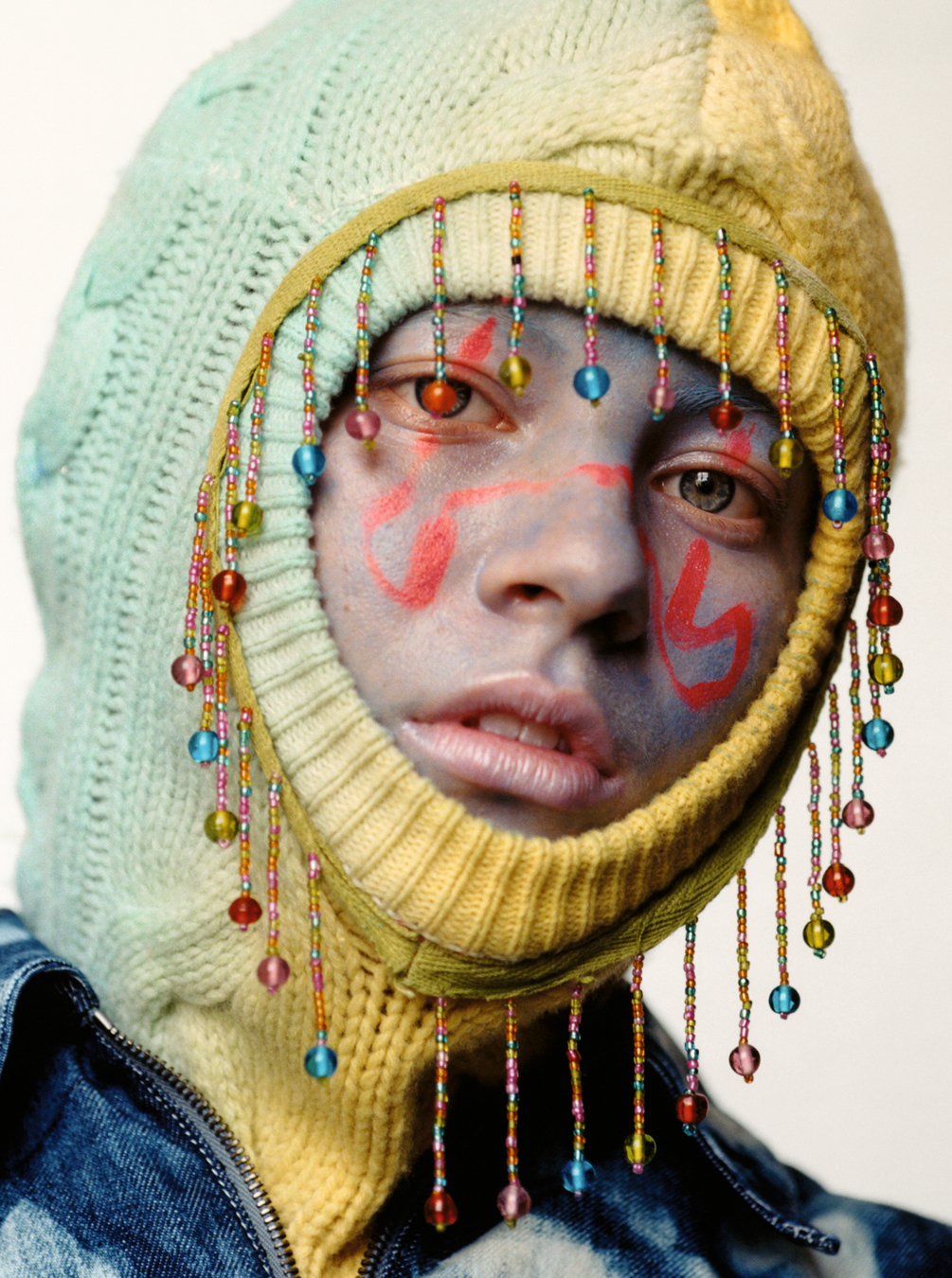 Lola + Pani photograph of a model wearing a balaclava with beats on it, with colourful facepaint on