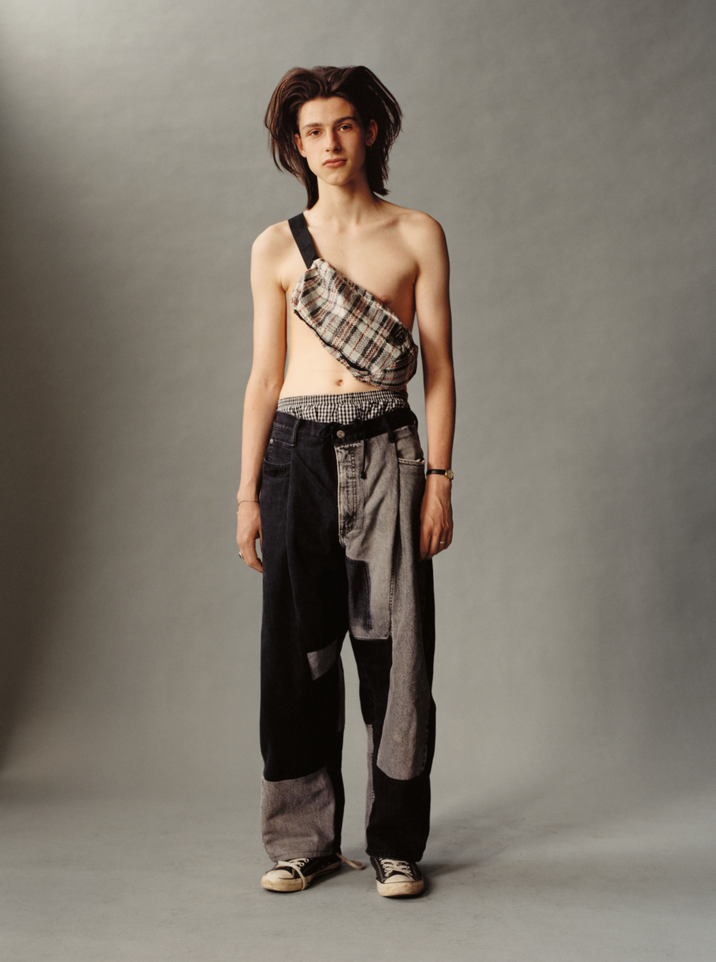 Lola + Pani photograph of a shirtless young model wearing patchwork jeans and a crossbody bag