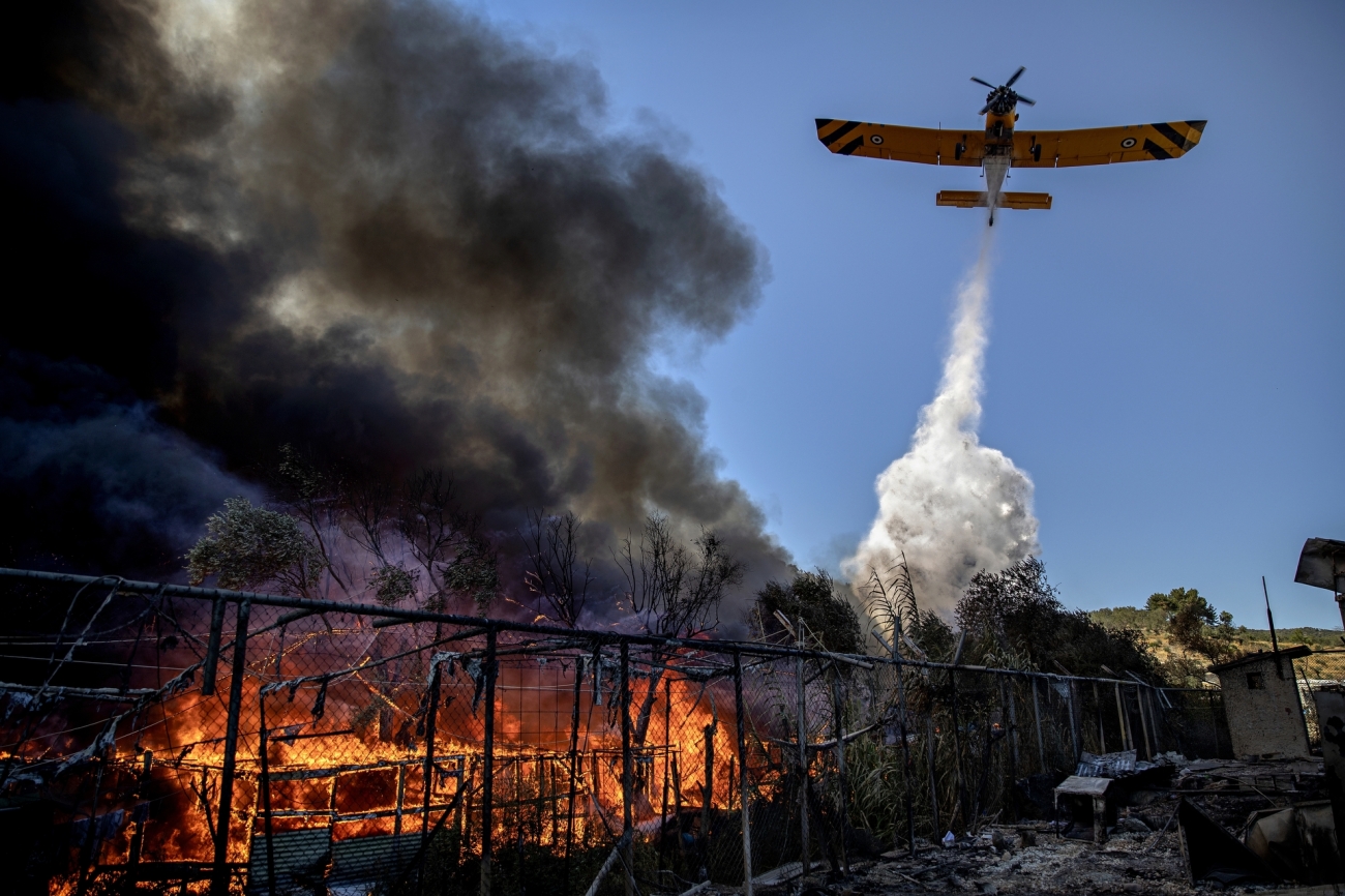 Karya fotografer Denmark Jacob Ehrbahn berjudul “Fire Destroys the Moria Camp 03” mengabadikan saat-saat pesawat memadamkan api yang melahap kamp pengungsi Moria pada 10 September 2020. Foto oleh Jacob Ehrbahn.