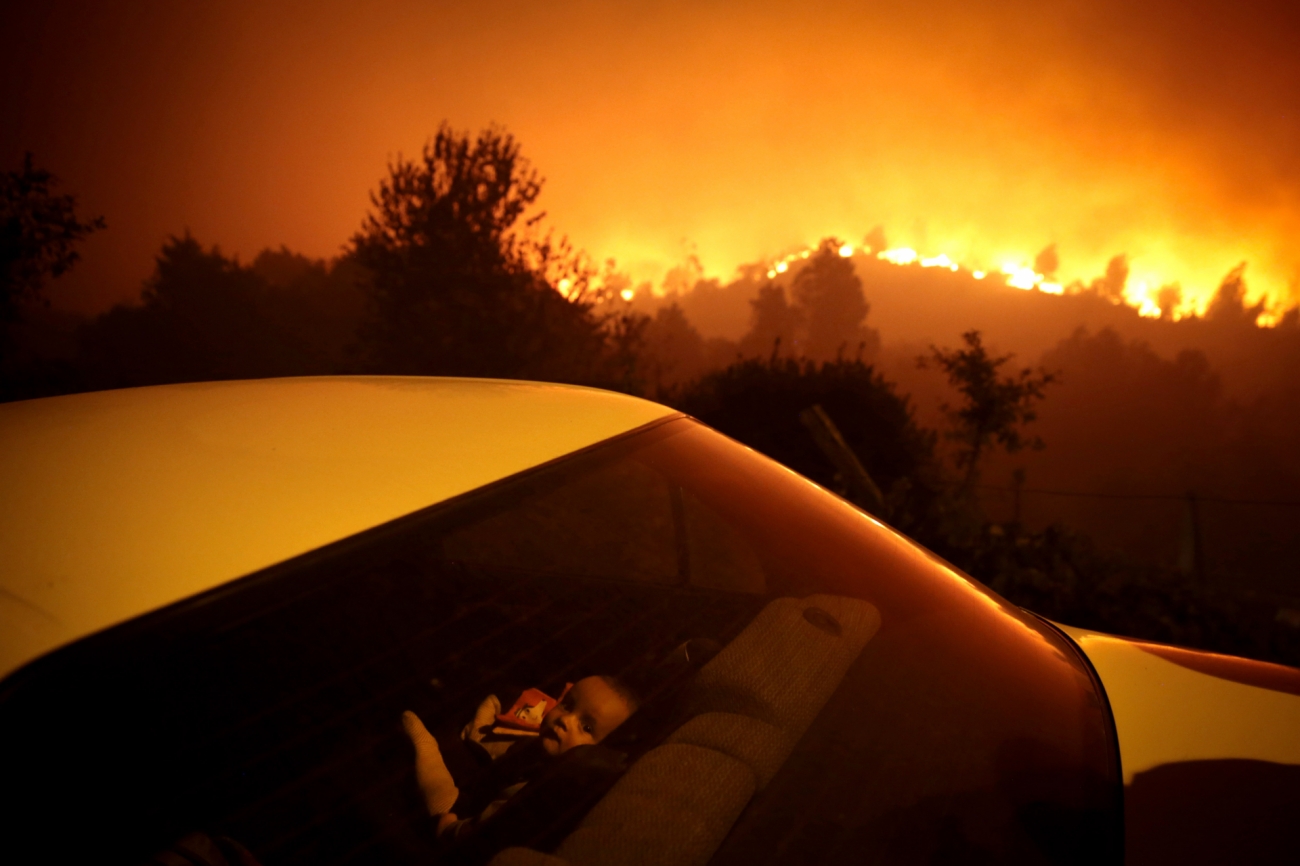 Karya fotografer Portugal Nuno André Ferreira berjudul “Portugal Forest Fire” mengabadikan kebakaran hutan yang berkobar sekitar 100 kilometer dari Porto. Seorang anak duduk di dalam mobil yang tak jauh dari lokasi kebakaran. Setiap tahun, ribuan hektar hutan di Portugal hangus secara tak terkendali. Foto oleh Nuno André Ferreira.