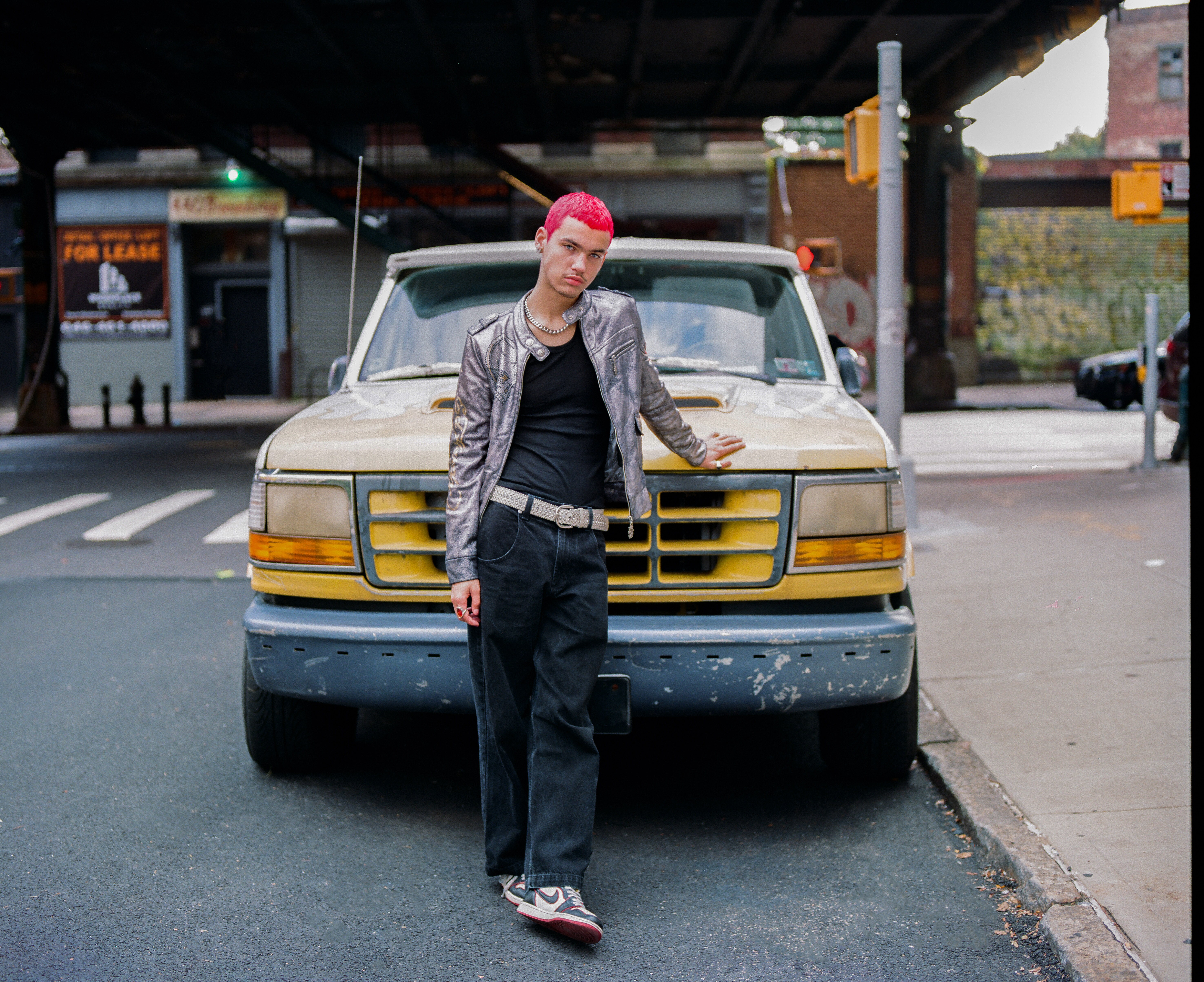 Boy with red hair poses in front of a car in Brooklyn